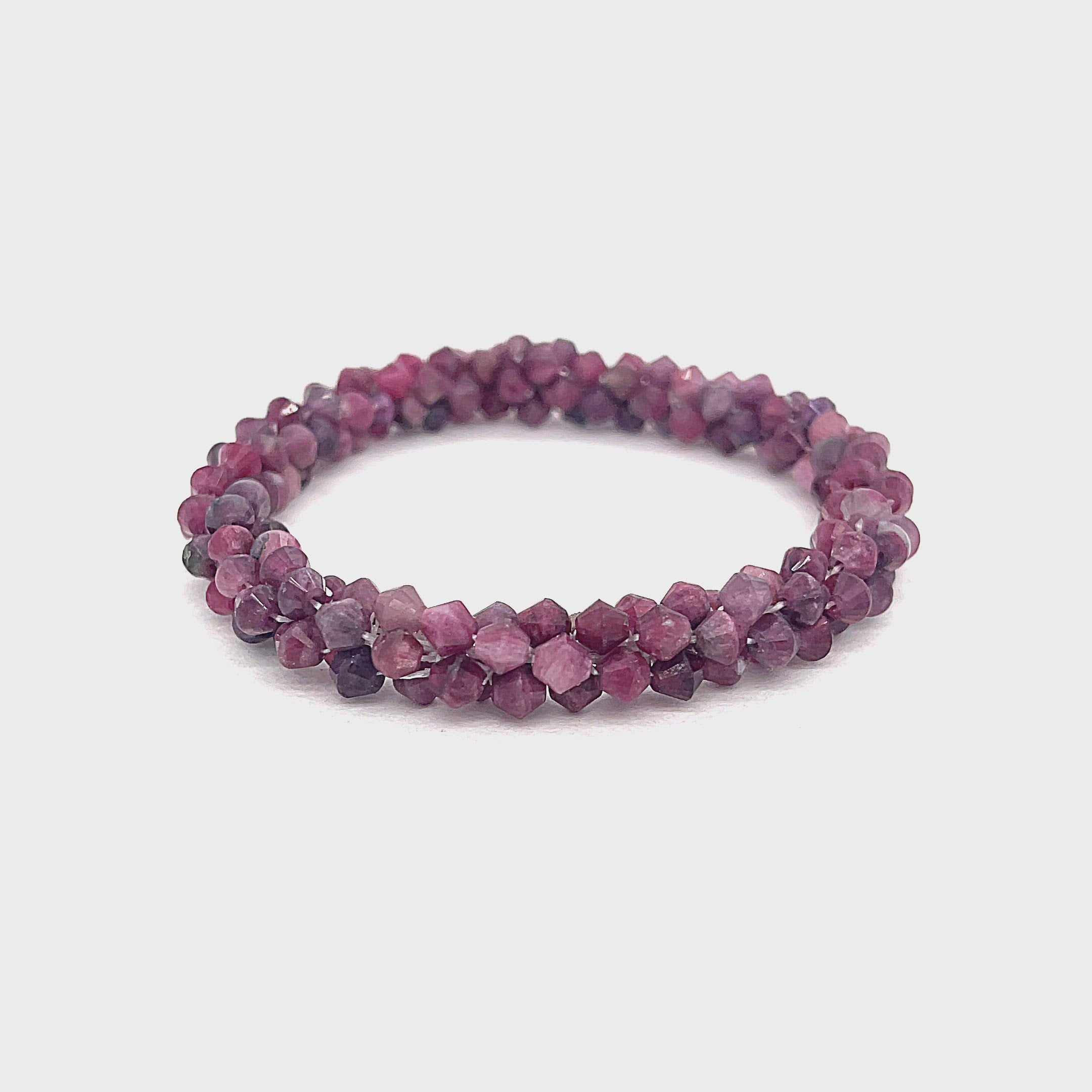 A crocheted bracelet made of pink tourmaline gemstones on a white background, front overview. video