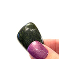A Asterite gemstone tumble displayed in a models hand on a white background, close-up overview.