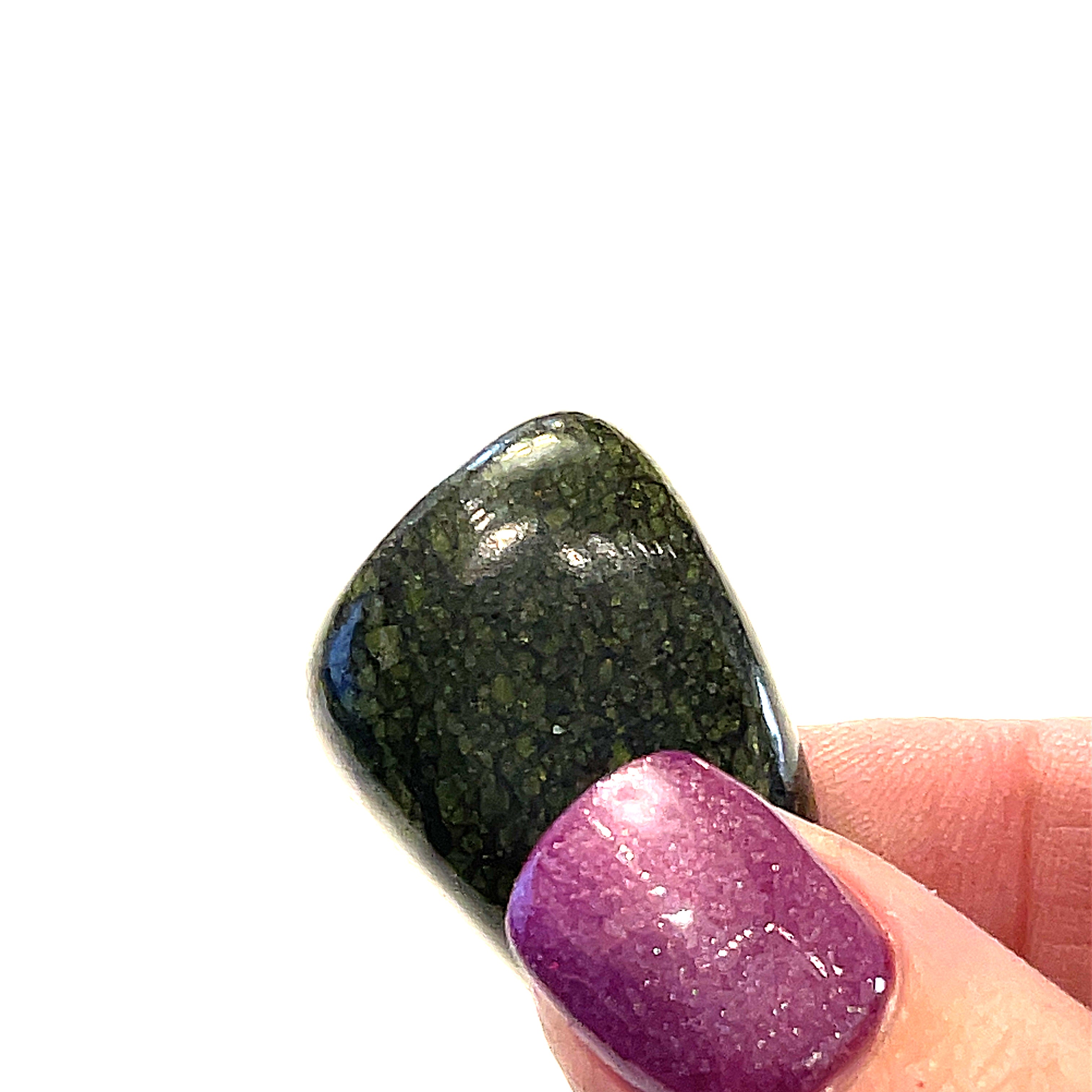 A Asterite gemstone tumble displayed in a models hand on a white background, close-up overview.