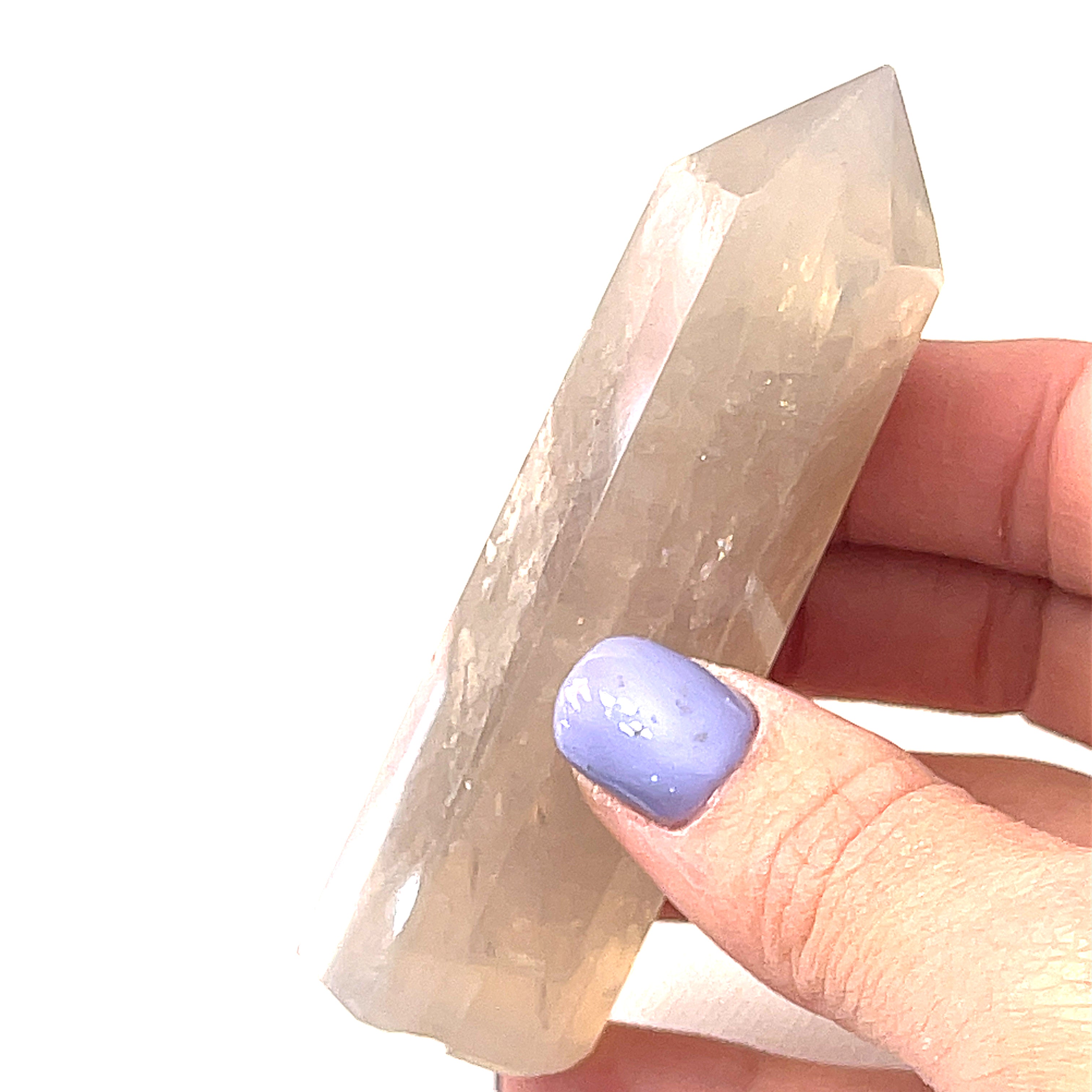 A  Blue Rose quartz gemstone towers arranged together on a white background in a models hand, front overview. 