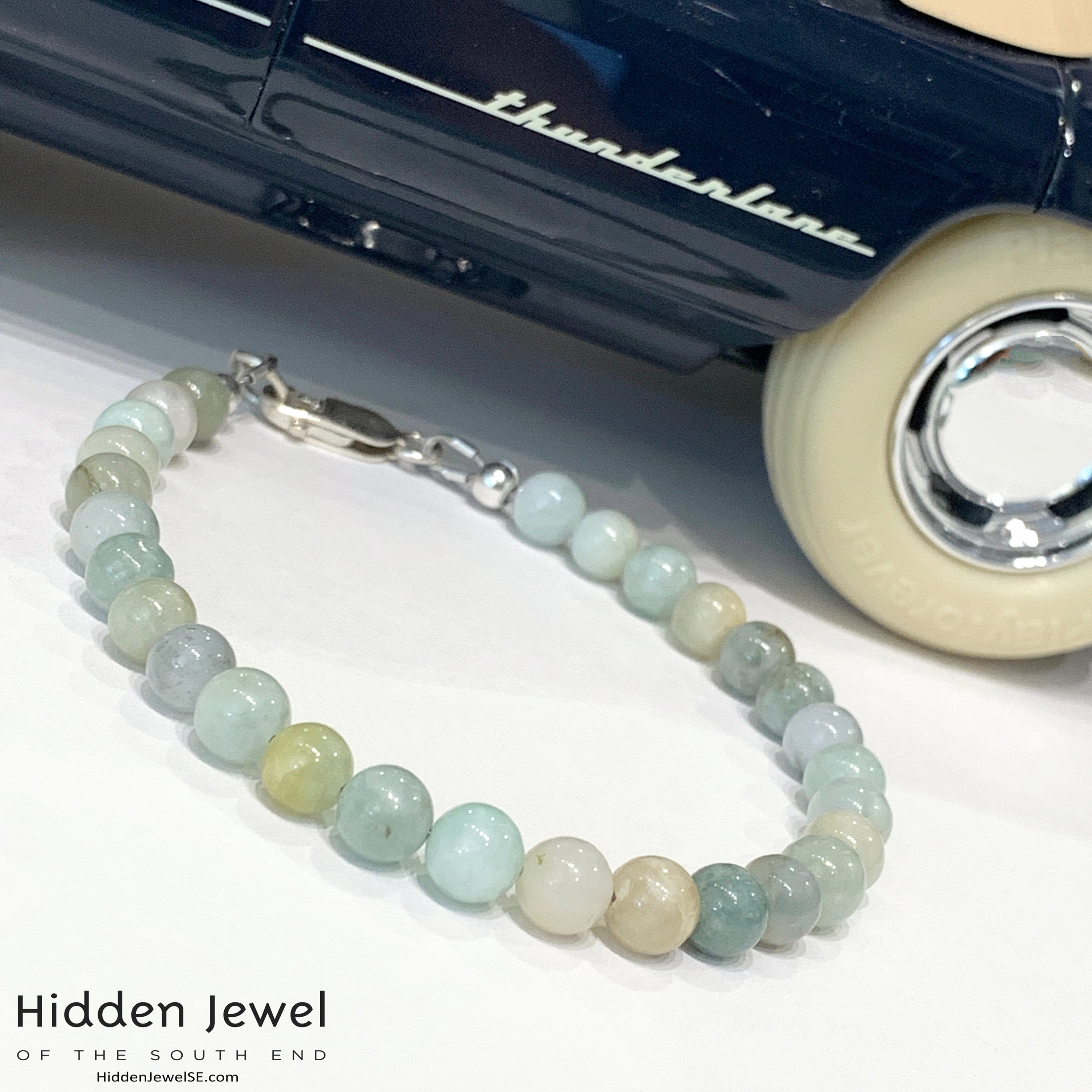 A Burma jade gemstone beaded bracelet with sterling silver  lobster claw on white background with a classic display car, front left angle overview. 