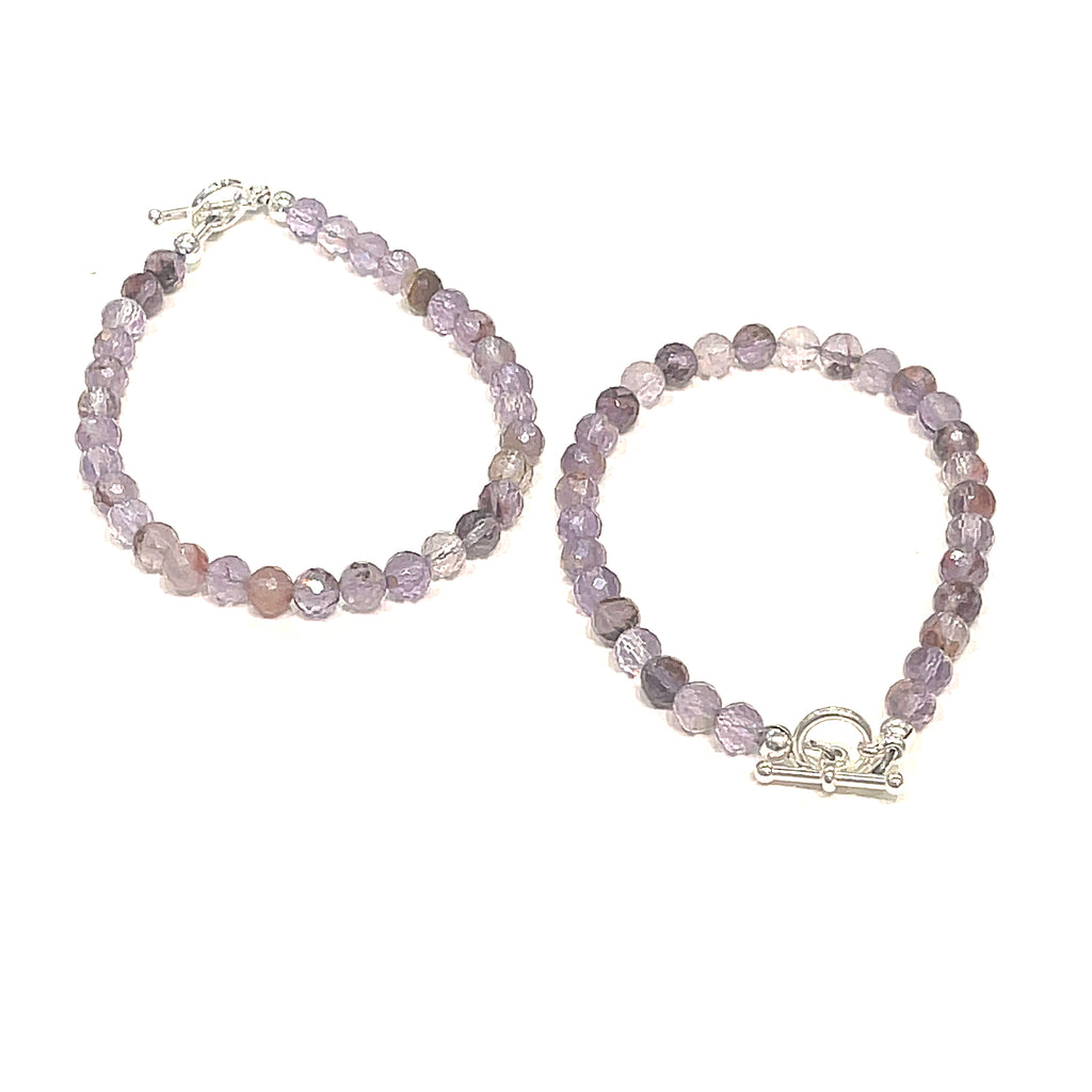 A Close-up of the Super Seven gemstone bracelet with 6mm faceted beads and a sterling silver toggle clasp. On a white background, center view. 