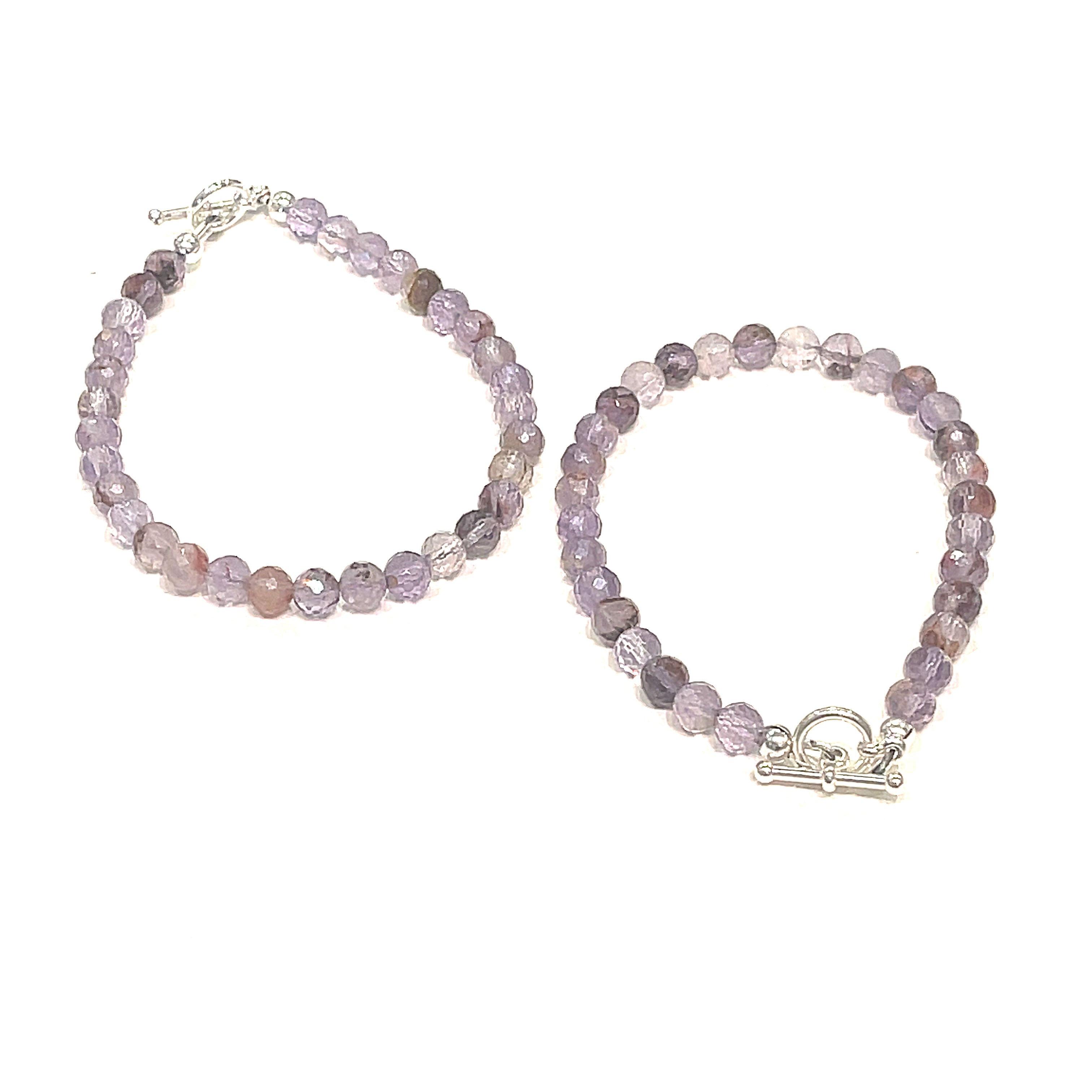 A Close-up of the Super Seven gemstone bracelet with 6mm faceted beads and a sterling silver toggle clasp. On a white background, center view. 