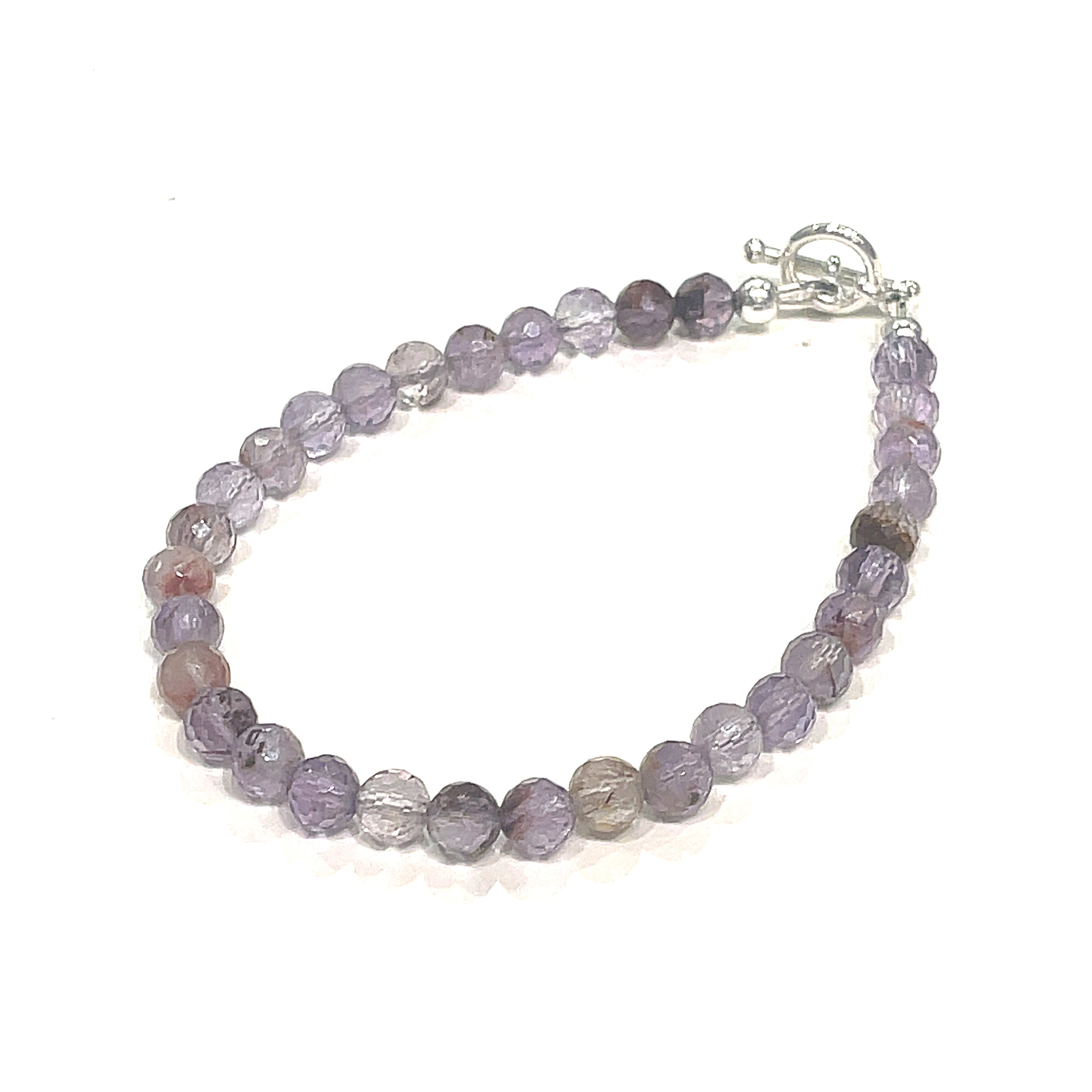 A Close-up of the Super Seven gemstone bracelet with 6mm faceted beads and a sterling silver toggle clasp. On a white background, front left angle view. 