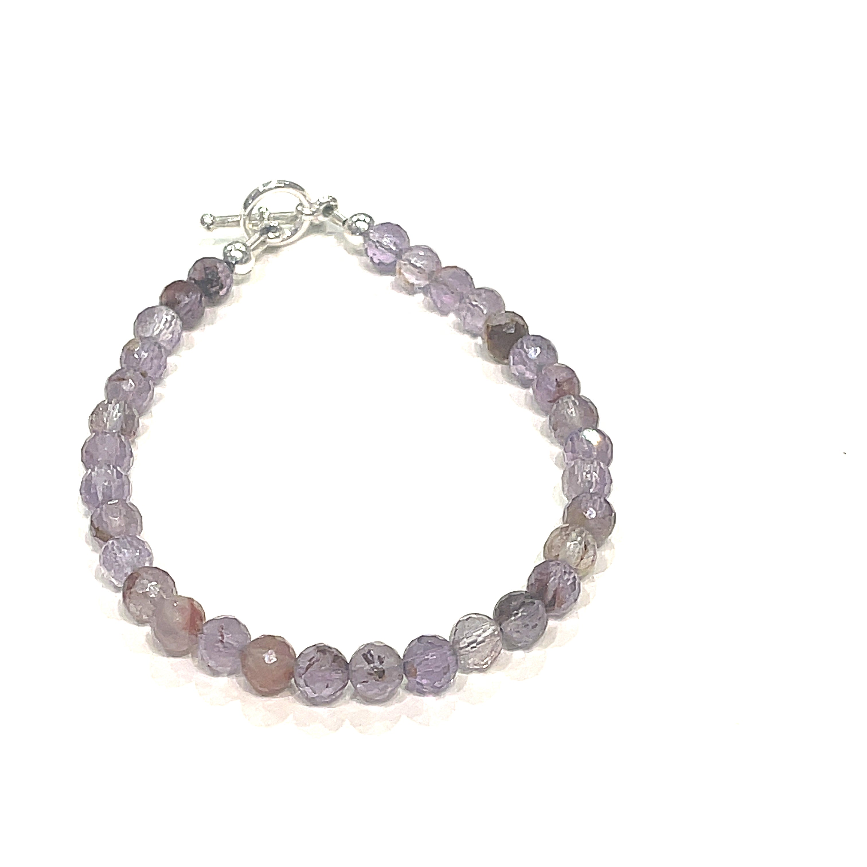 A Close-up of the Super Seven gemstone bracelet with 6mm faceted beads and a sterling silver toggle clasp. On a white background, front view. 