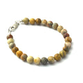 A Crazy Lace Agate gemstone beaded bracelet with sterling silver lobster claw on a white background front right angle overview. 