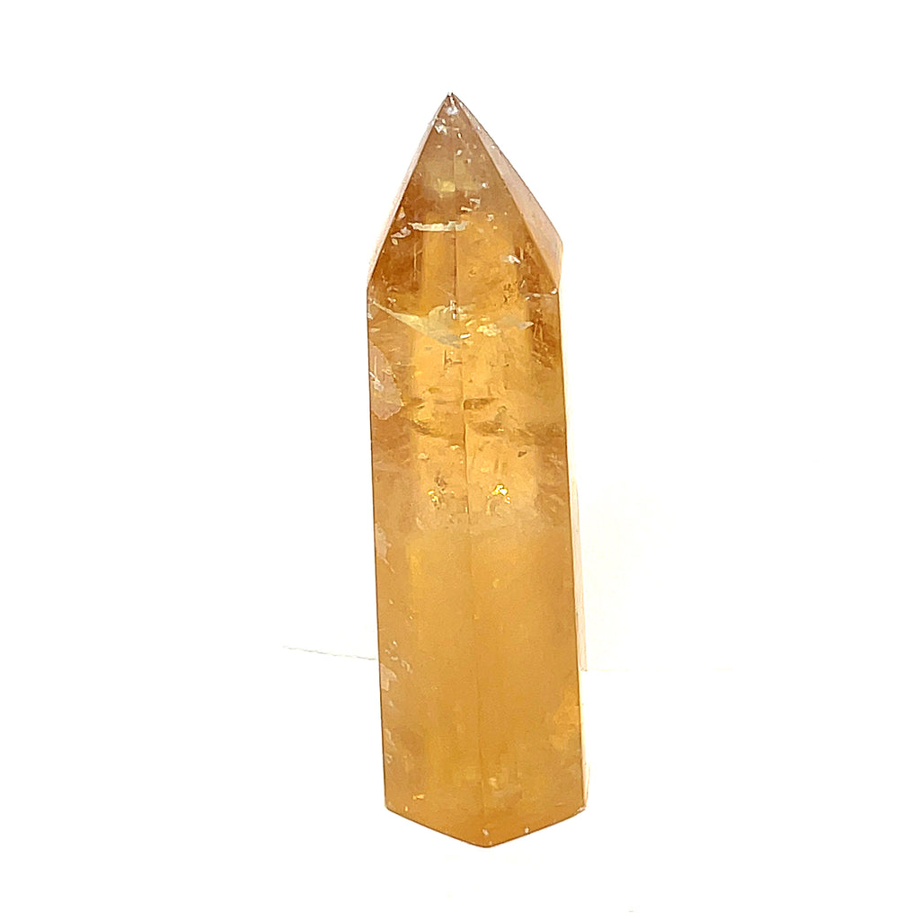 A Honey Calcite gemstone tower displayed on a white background, front view.