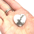 A Howlite gemstone with a white and gray marbled pattern displayed on a models palm on a white background, front view. 