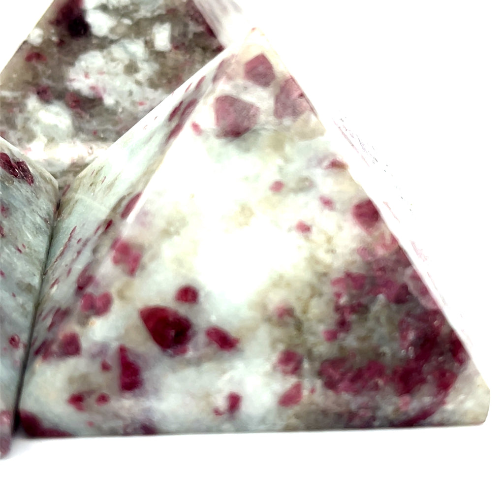 A Pink Tourmaline Pyramid used for heart chakra meditation and energy healing on a white background front close up overview.