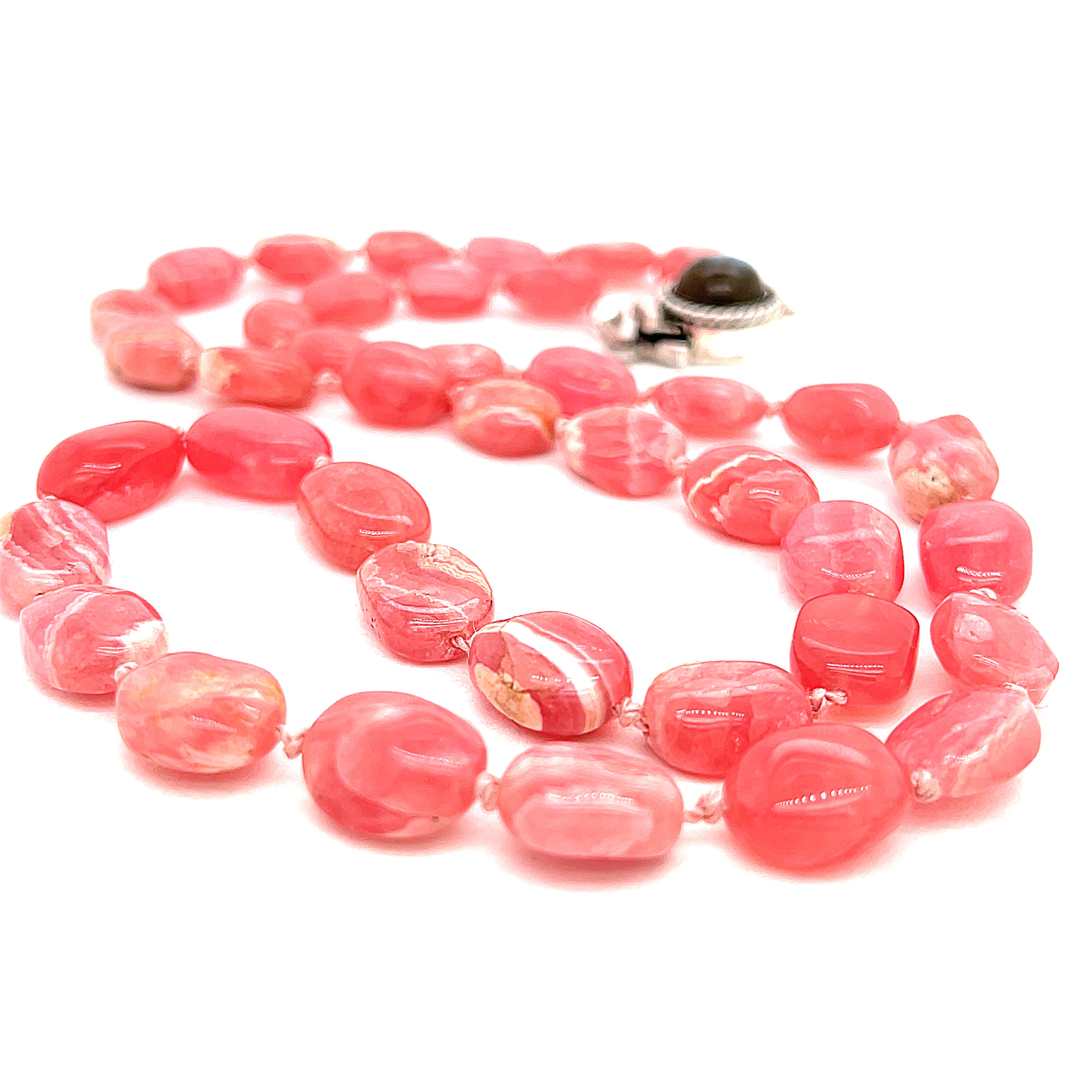 A Rhodochrosite gemstone knotted necklace with a sterling silver Labradorite gemstone box clasp, on a white background, middle, long close up overview.