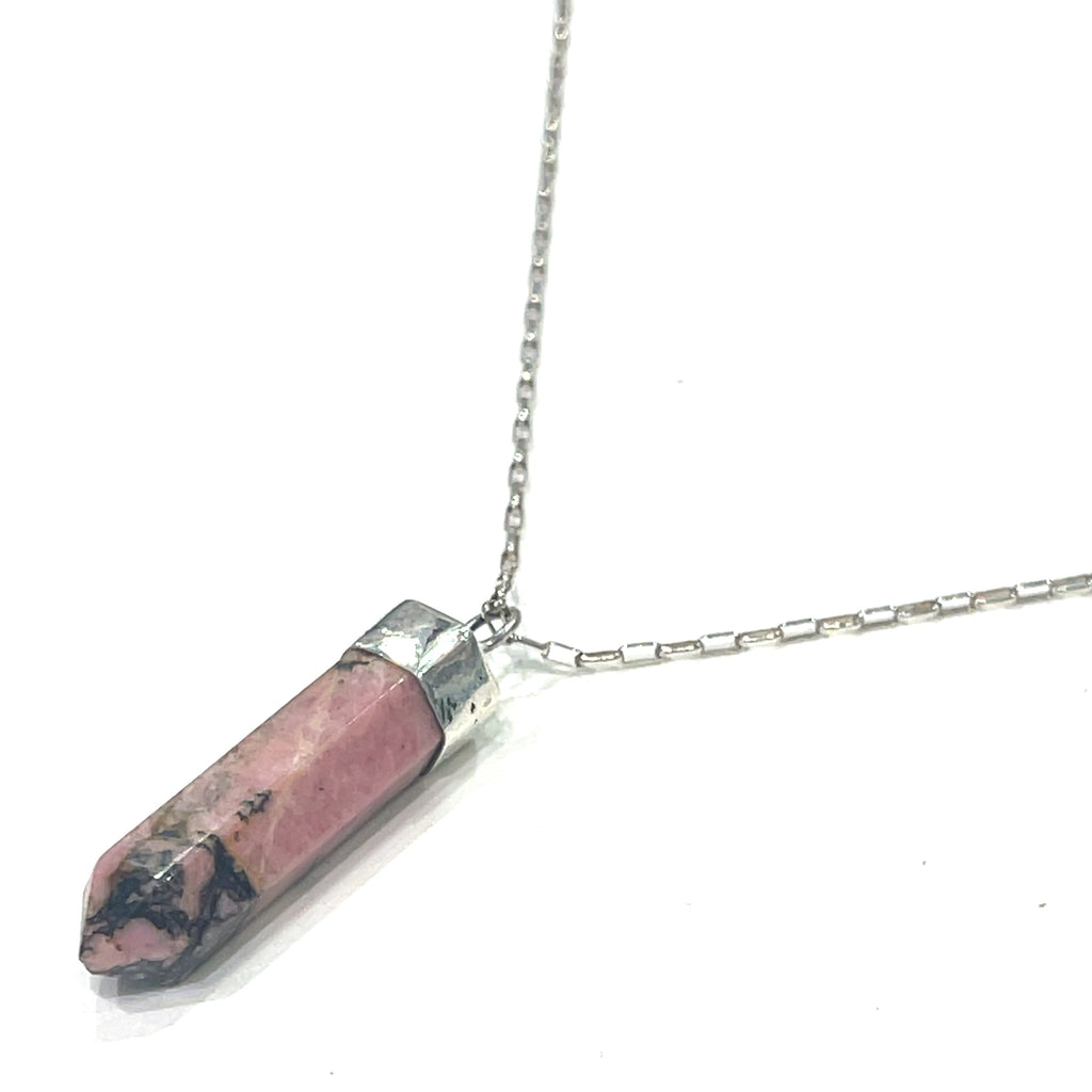 A Rhodonite gemstone pendant on a sterling silver chain. On a white background and hung on a left angle overview. 