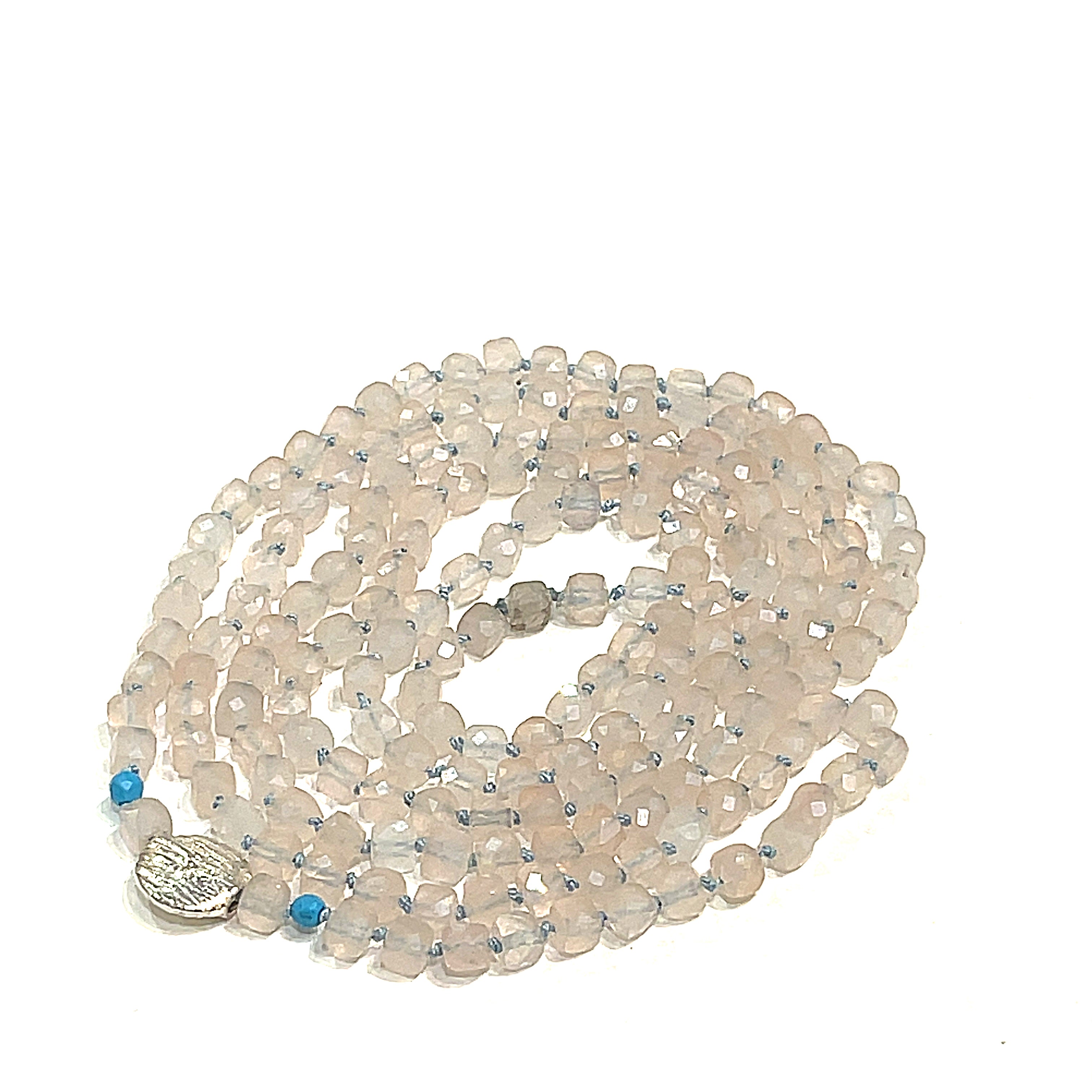A Rose Quartz and Turquoise knotted necklace with sterling silver beads, on a white background, front, circle close-up overview. 