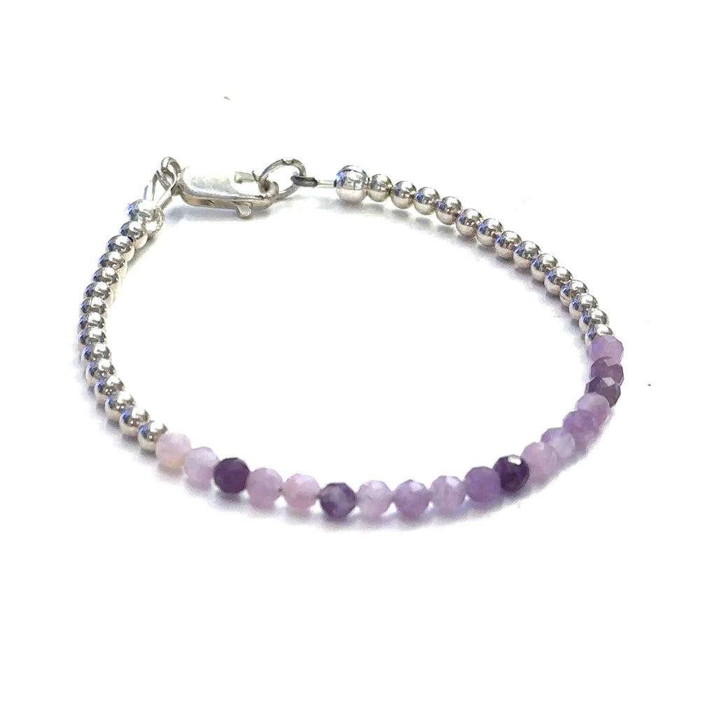 A Sugilite gemstone bracelet with a sterling silver clasp, featuring tiny faceted gemstones in shades of purple and pink on a white background, front view.