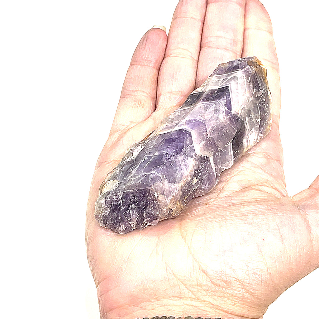 A XL size raw Amethyst or Prasiolite gemstones on a white background, on a models palm, front overview.