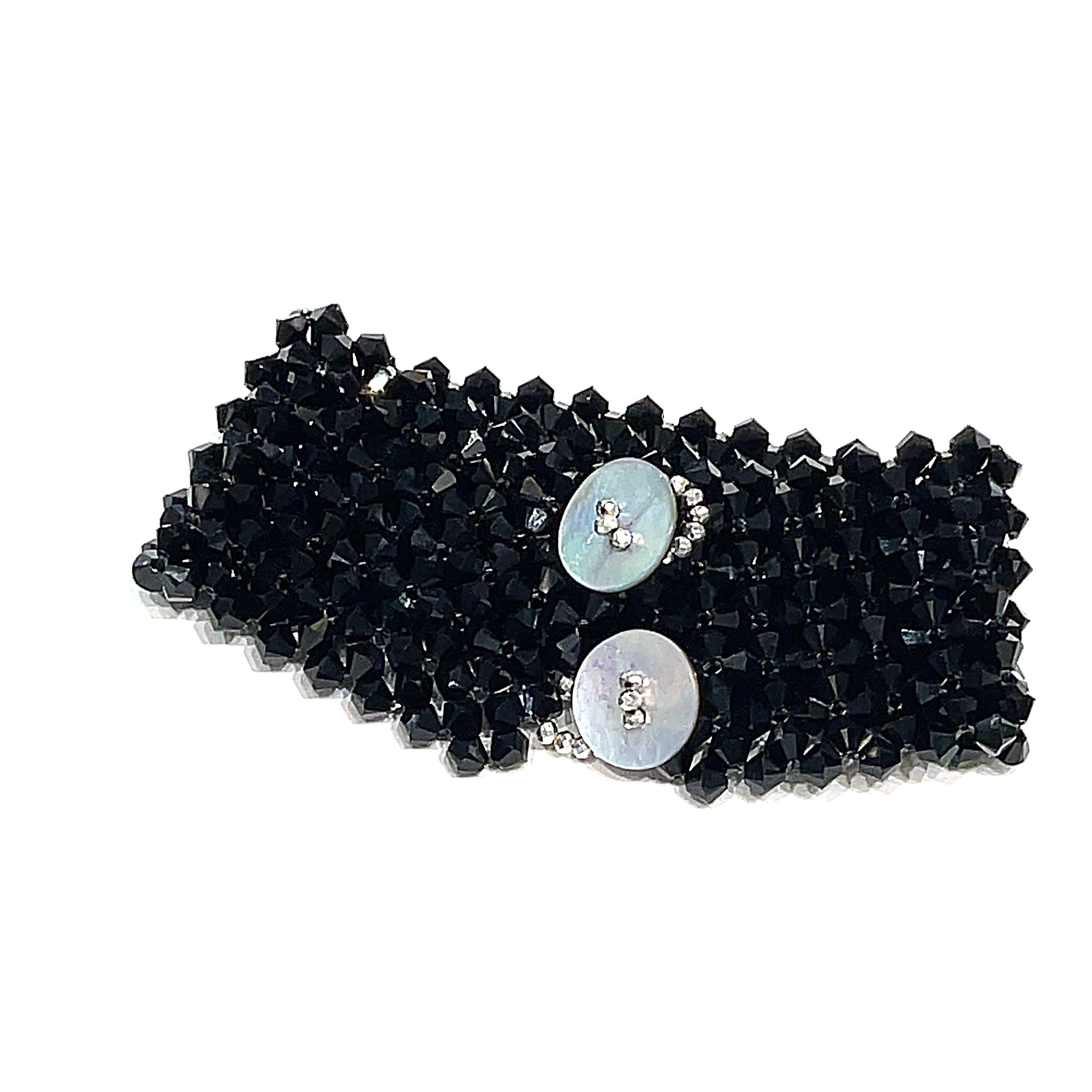 A black colored Swarovski crystal cuff bracelet with abalone shell and silver-coated pyrite buttons at the center back view on a white background.