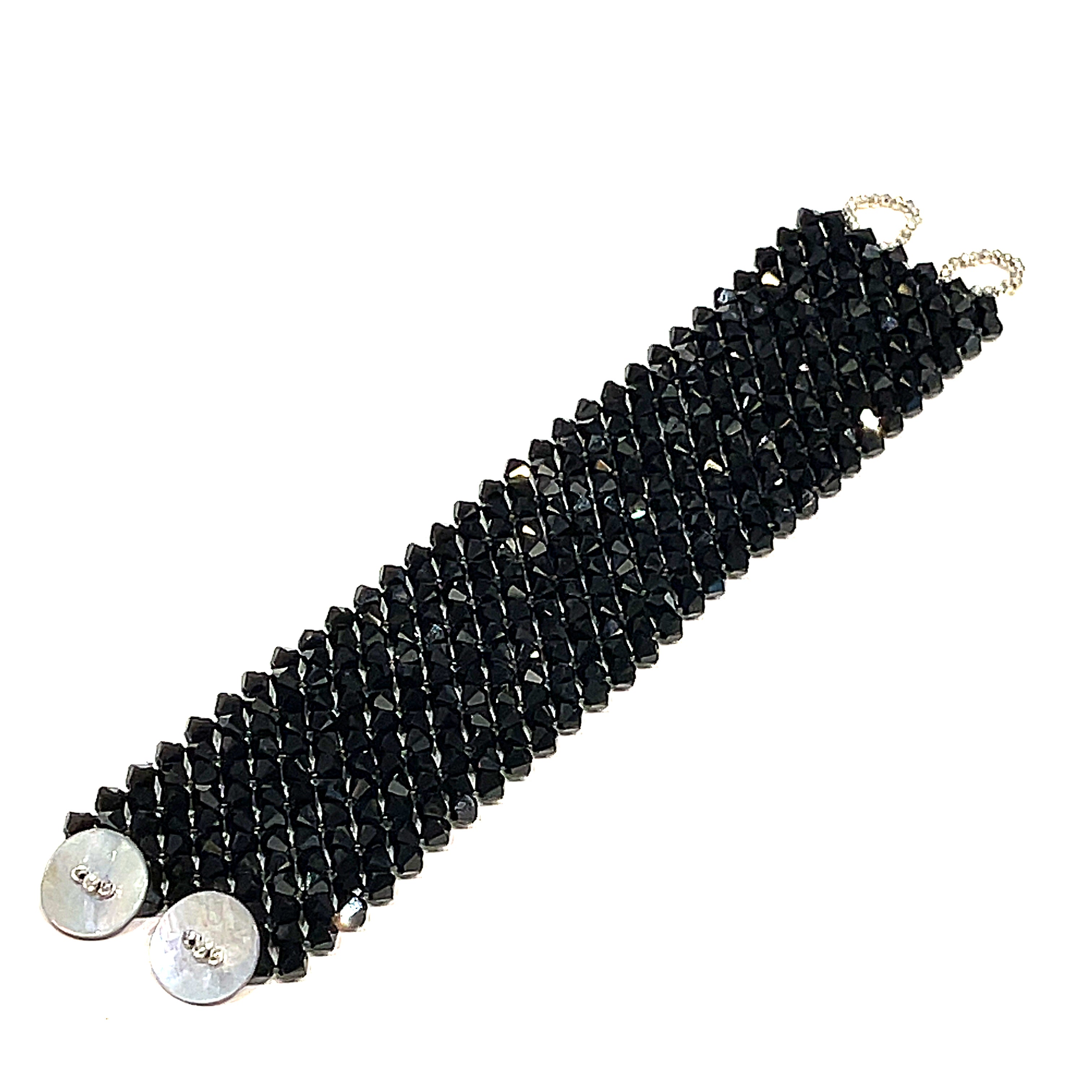 A black colored Swarovski crystal cuff bracelet with abalone shell and silver-coated pyrite buttons at the center long  view on a white background.