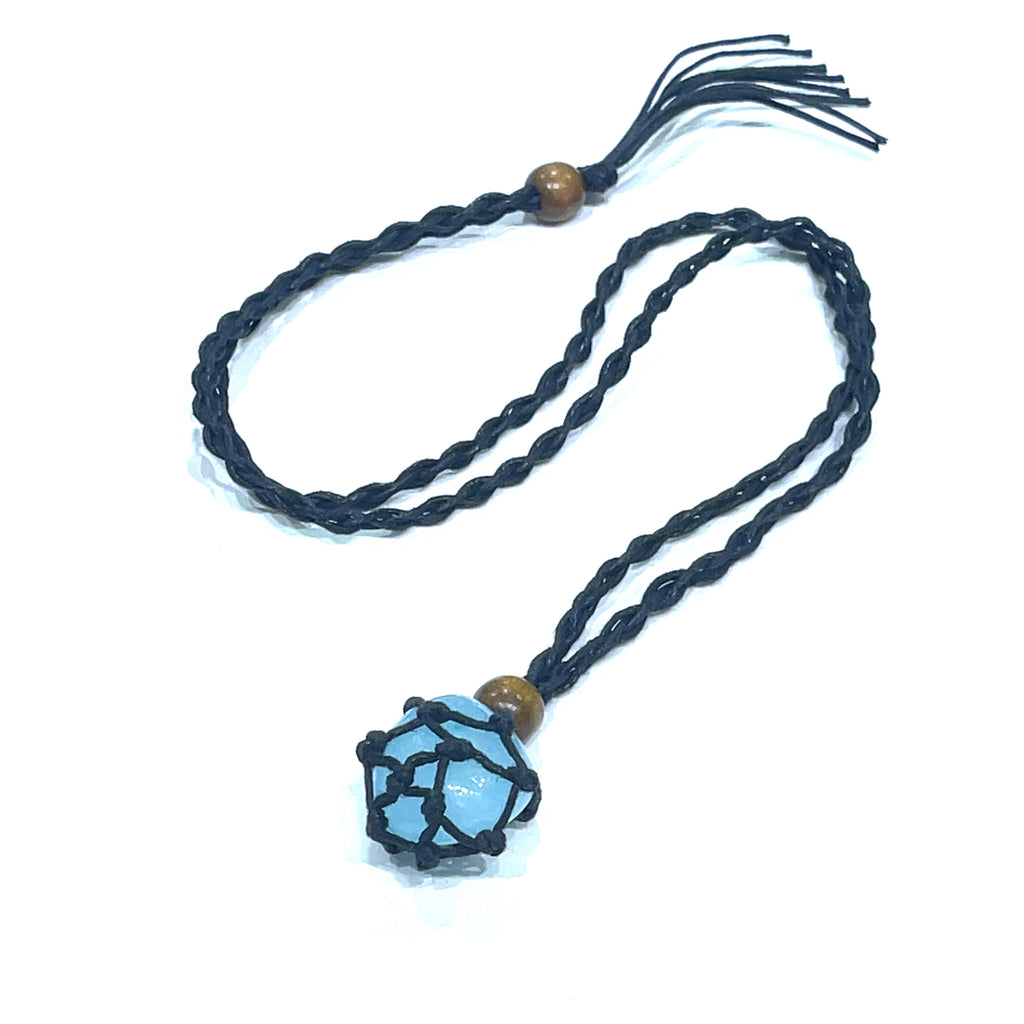 A black macramé necklace cord with a blue gemstone cage pendant on a white background, center overview. 