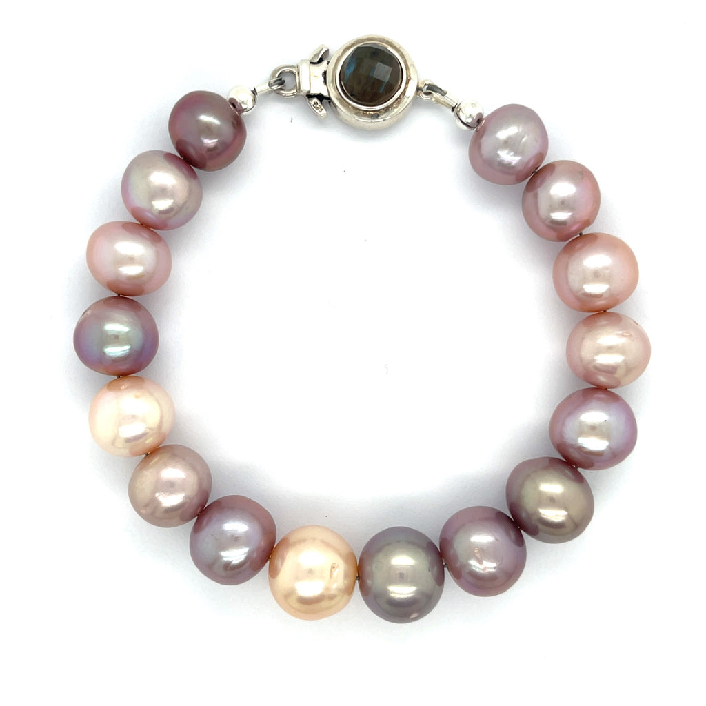 A bracelet made of Edison pearls, featuring a mix of pearl and peal beads, with a sterling silver box clasp and a bezel set labradorite gemstone on a white background, front overview.