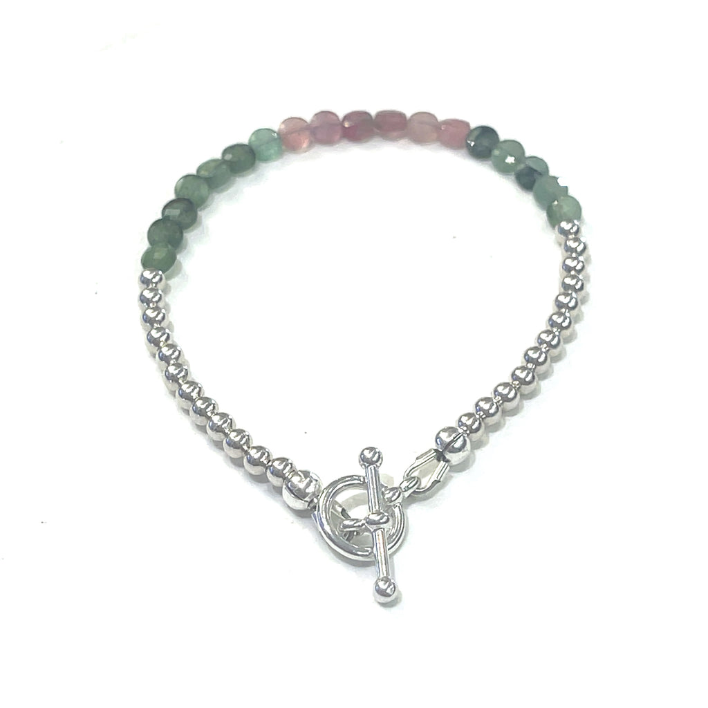 A bracelet with faceted watermelon tourmaline circles and sterling silver beads, featuring a sterling silver toggle clasp, on a white background back overview. 