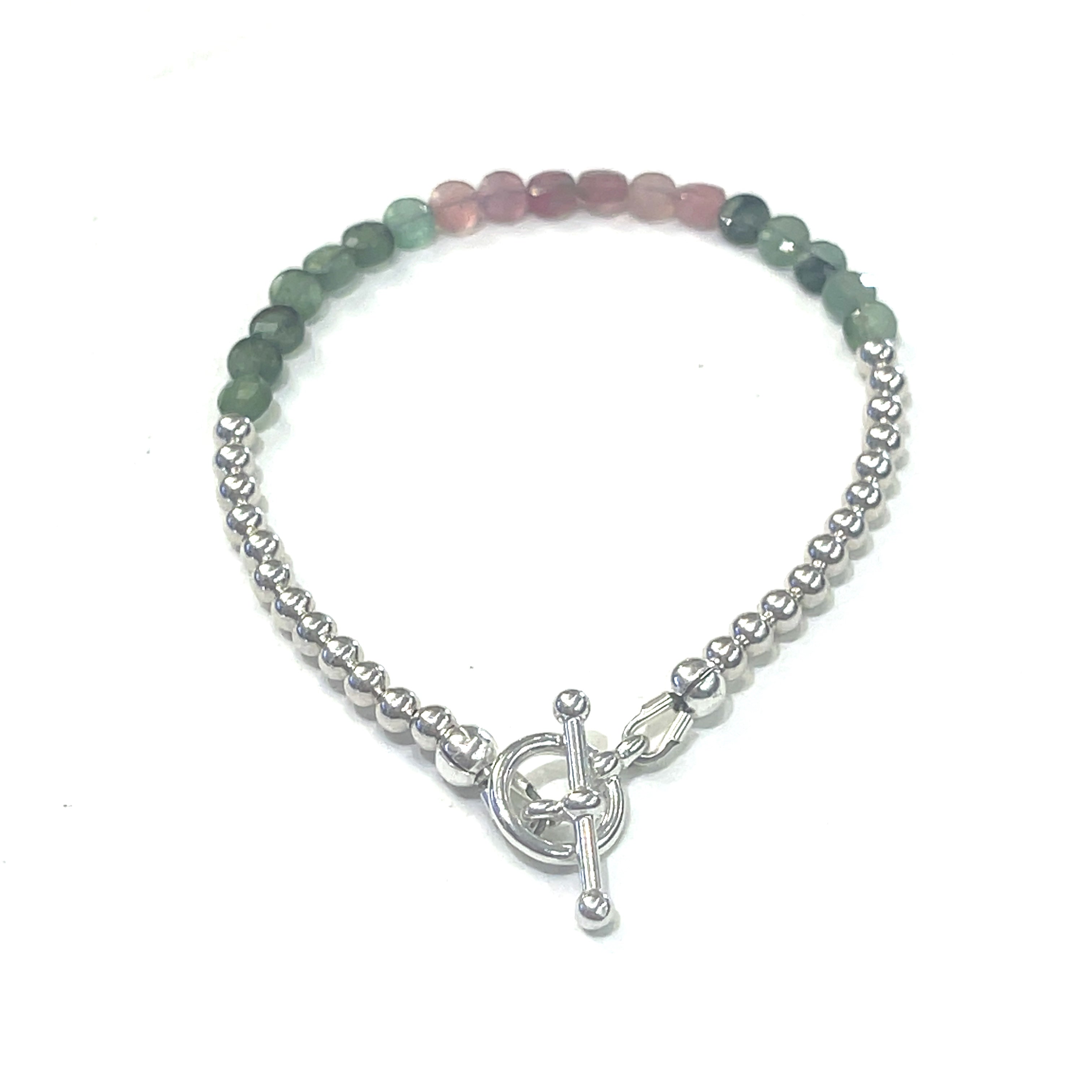 A bracelet with faceted watermelon tourmaline circles and sterling silver beads, featuring a sterling silver toggle clasp, on a white background back overview. 