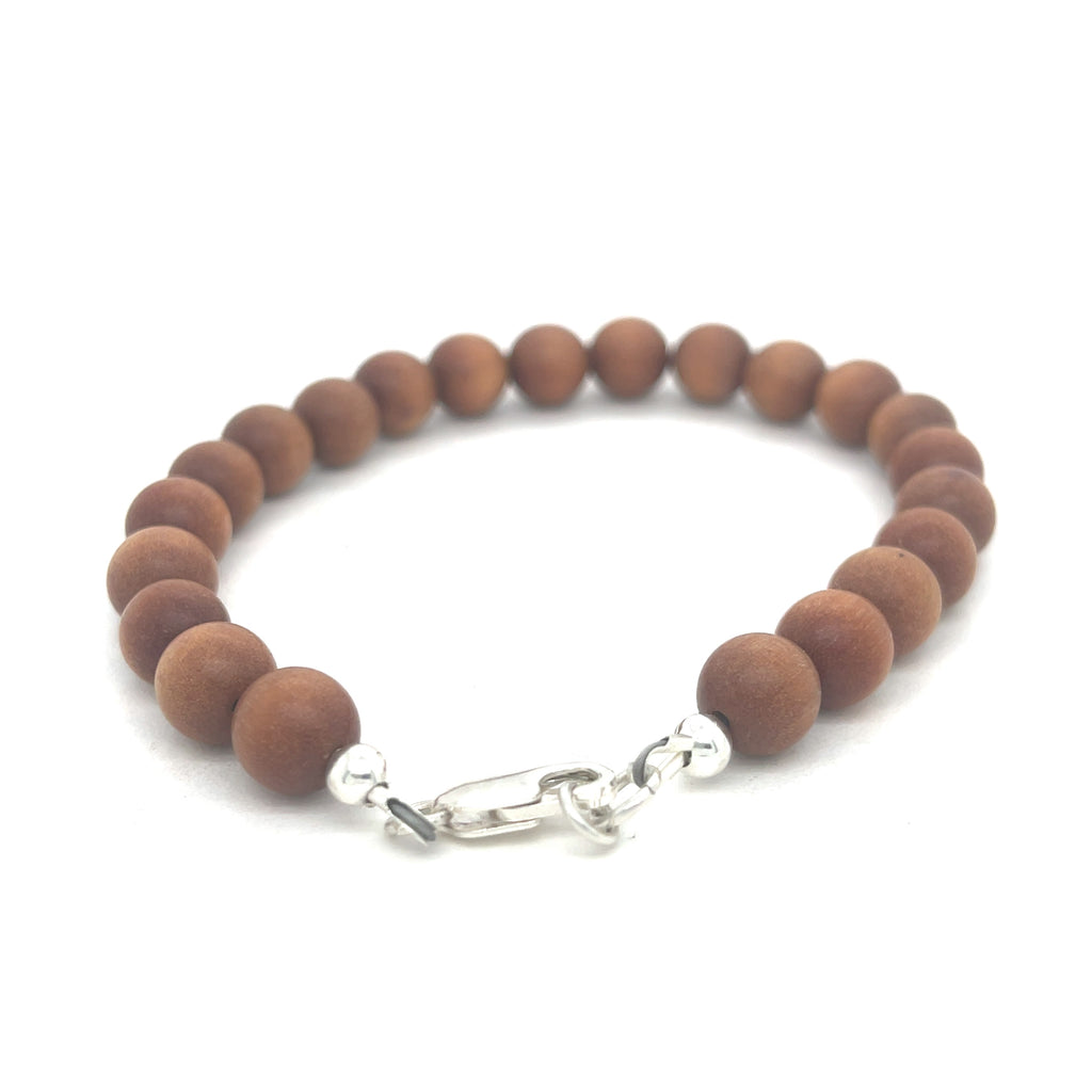 A brown sandalwood beaded bracelet with a sterling silver lobster-claw clasp on a white background, back center view.
