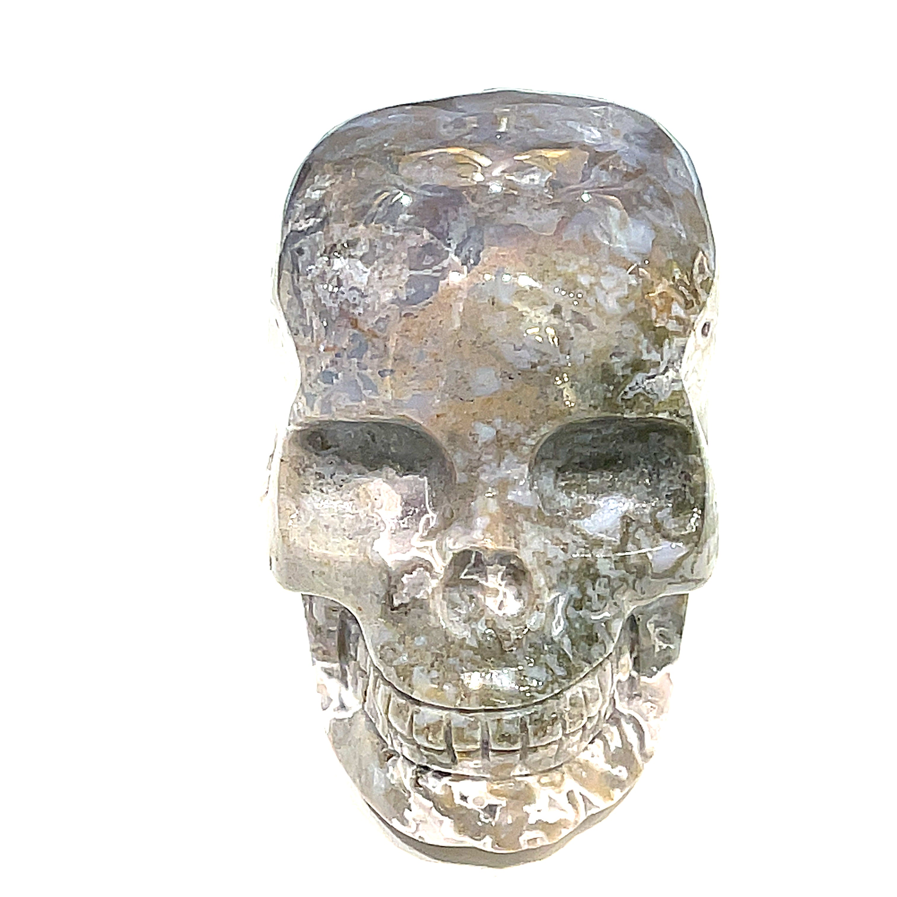 A carved gemstone skull, predominantly white in color with green accents, showcasing realistic facial features on a white background, front close up view. 