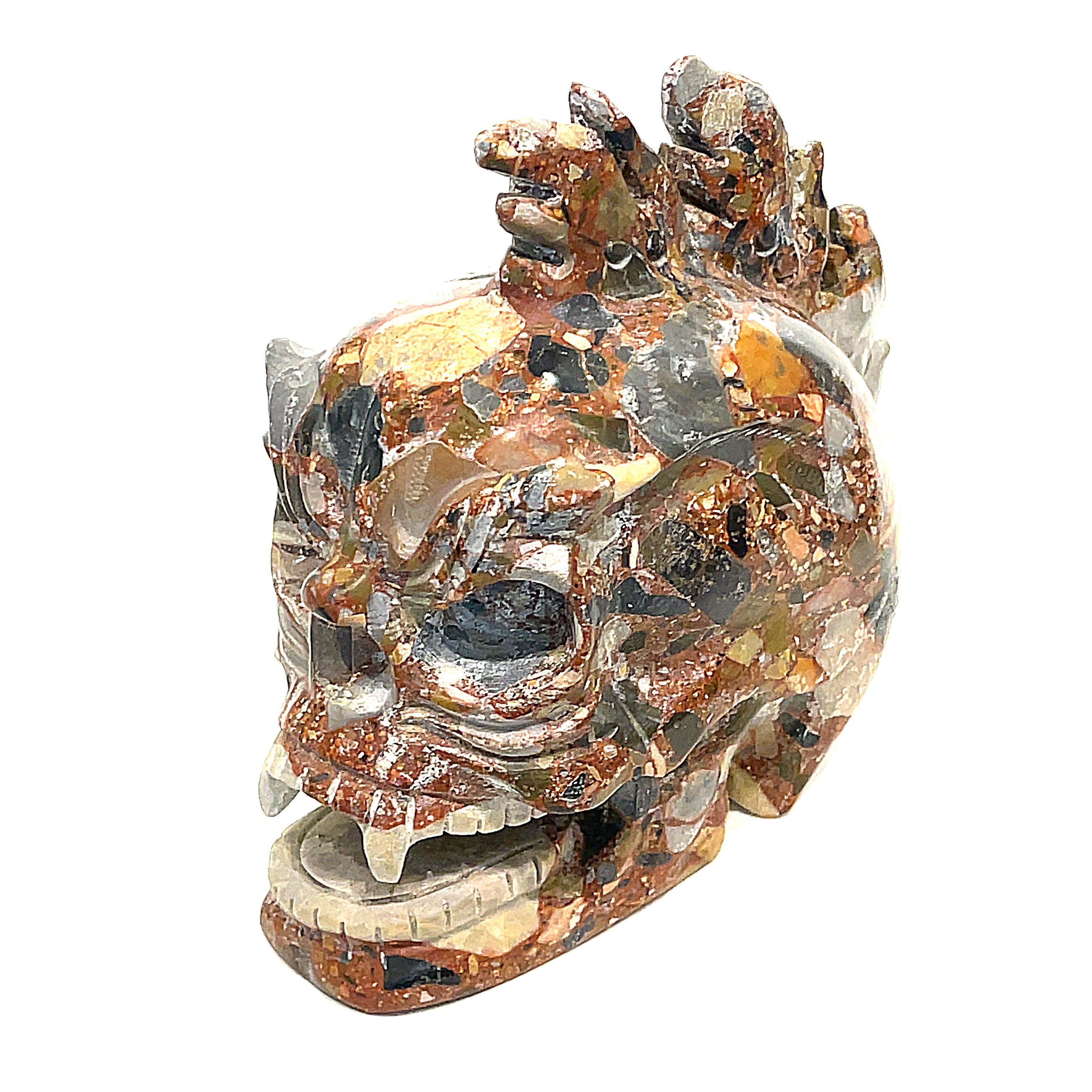 A carved jasper skull alter stones with a dragon mohawk design on a white background,  left-side angle front view. 