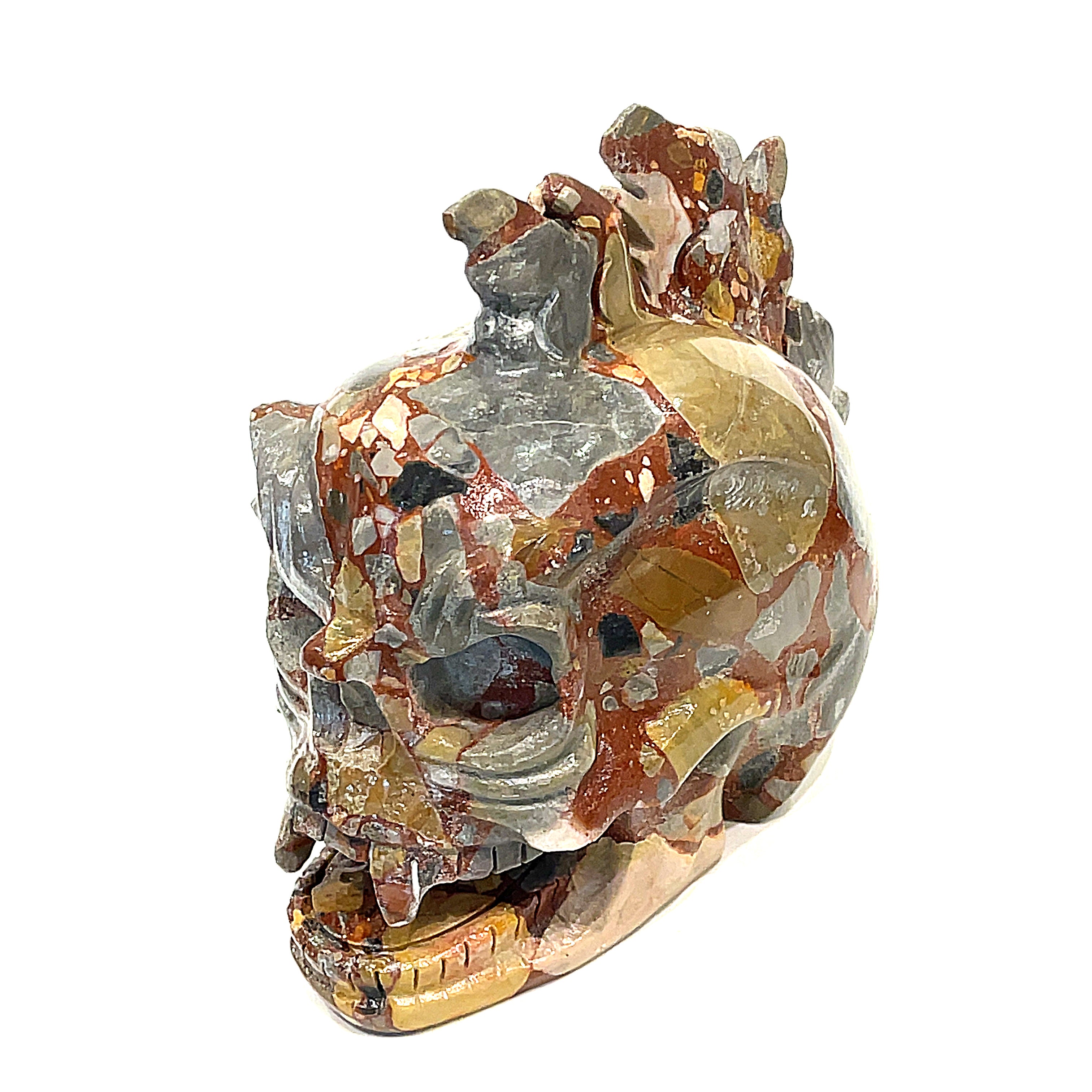 A carved jasper skull alter stones with a dragon mohawk design on a white background, slightly left-angle front view. 