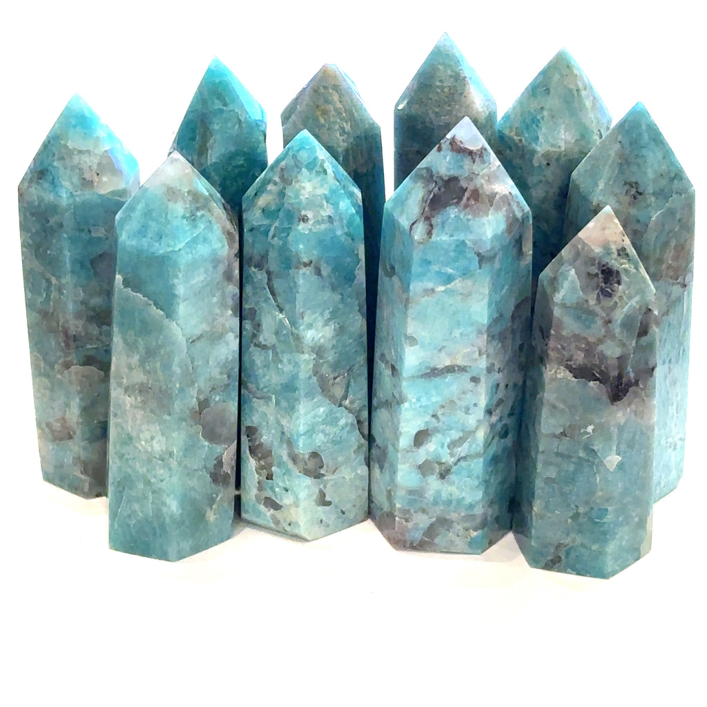 A collection of Amazonite gemstone towers displayed in a row, showcasing their blue color and crystalline structure on a white background front view