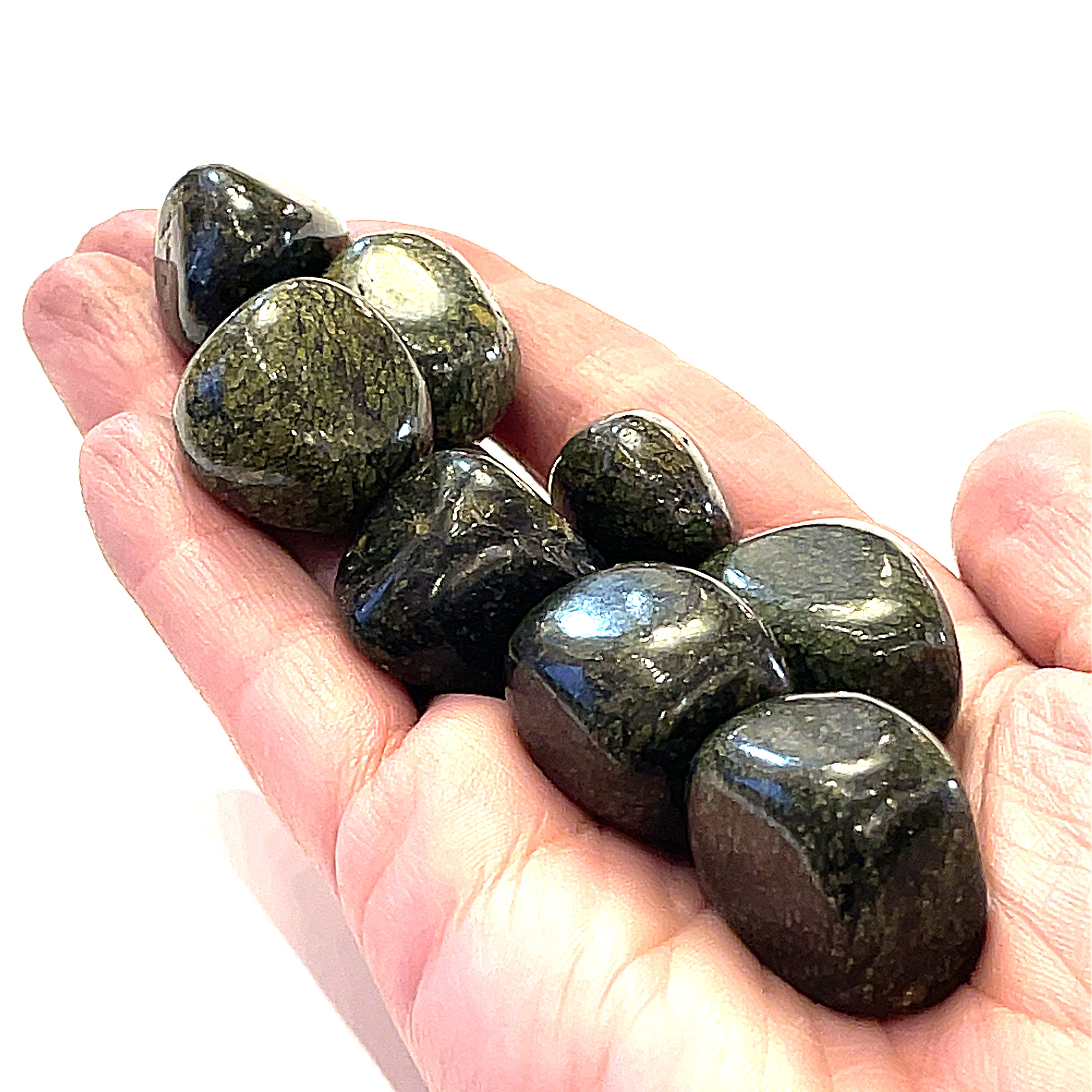 A collection of Asterite gemstone tumbles displayed in a models hand on a white background, close-up overview.