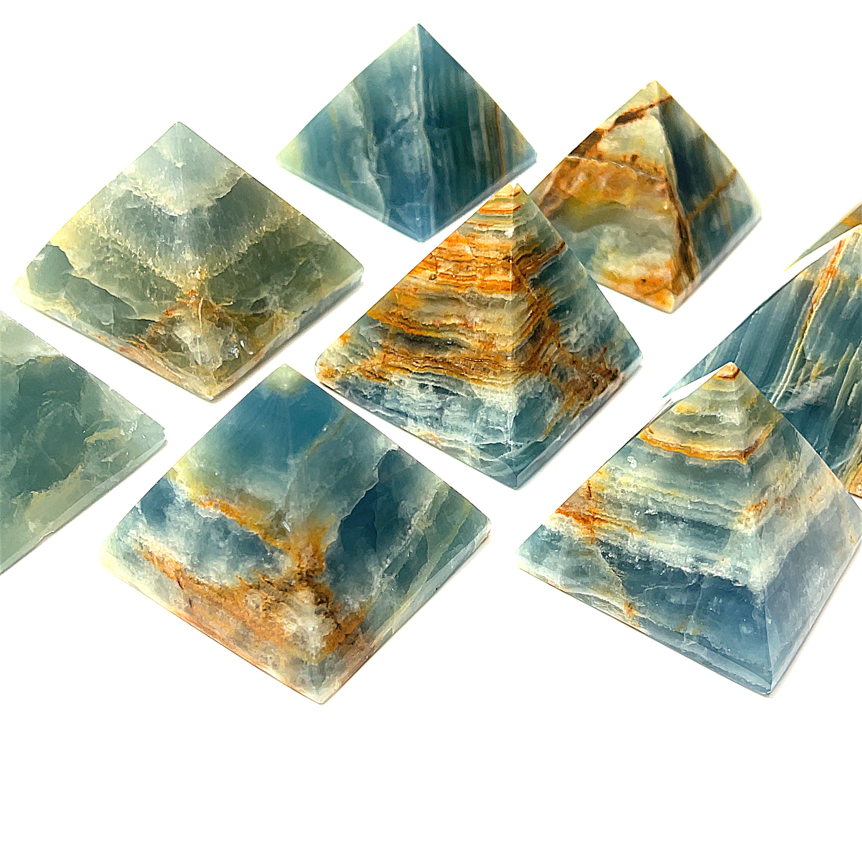 A collection of Blue Onyx gemstone pyramids of various sizes arranged on a white background, center front, close up overview.
