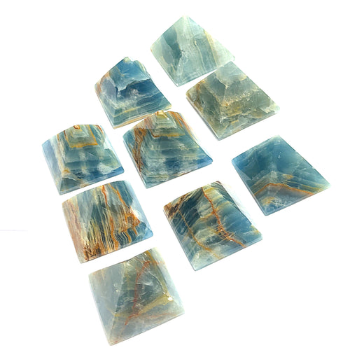 A collection of Blue Onyx gemstone pyramids of various sizes arranged on a white background, center front, overview.