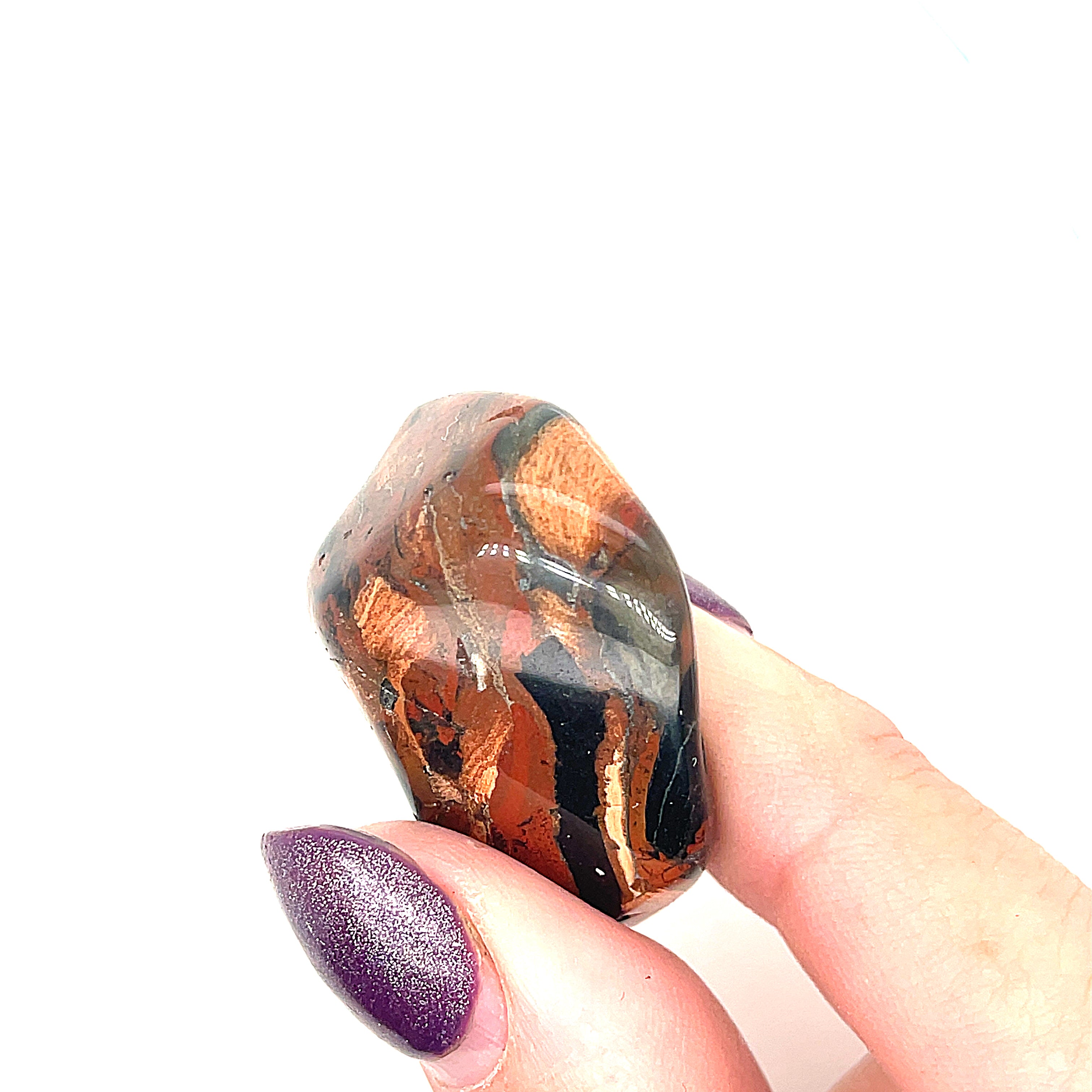 A collection of Brecciated Jasper tumbled gemstones displayed on a white background, front, close-up overview in a models finger tips.