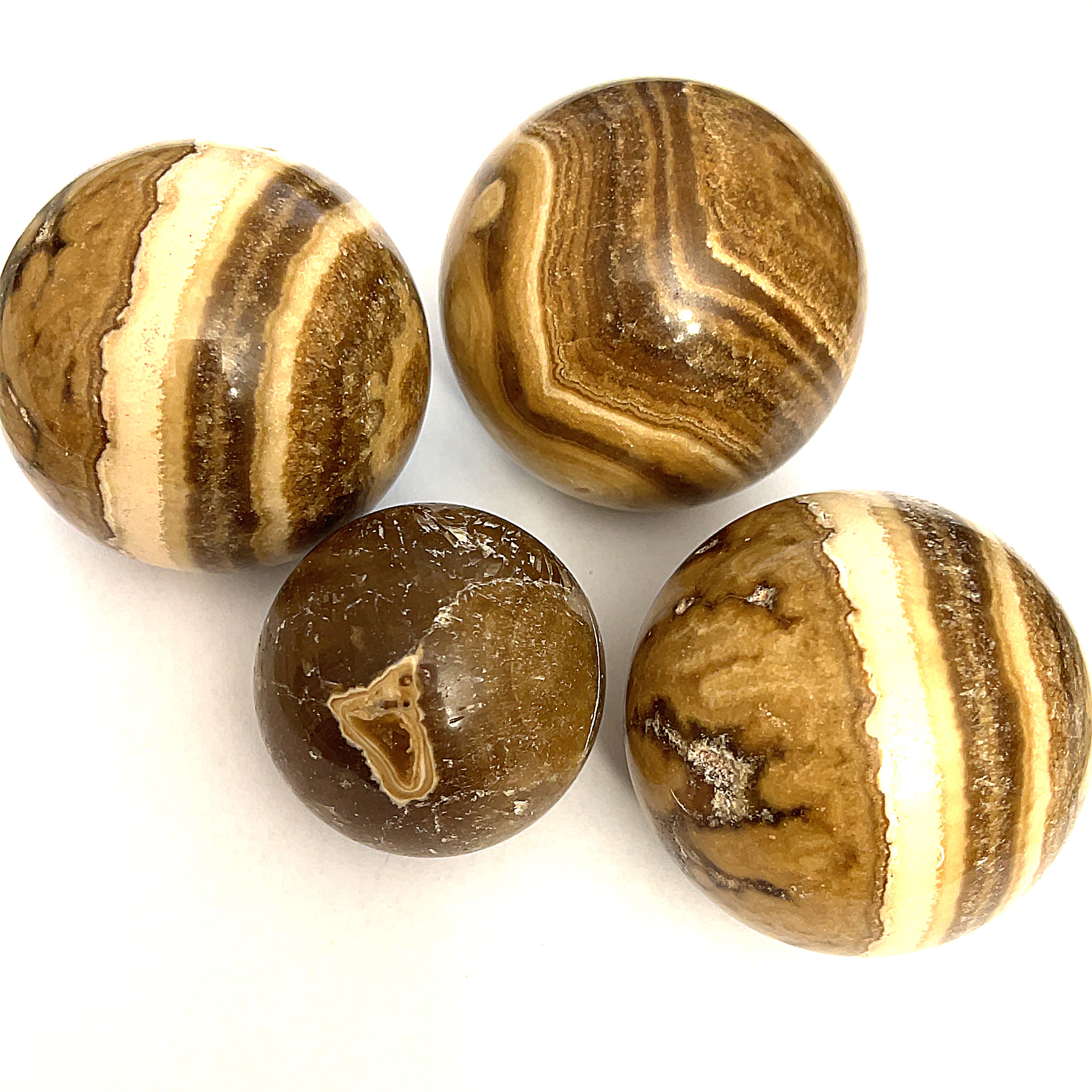 A collection of Chocolate Calcite Gemstone Spheres with varying shades of brown and white bands, displayed on a white surface, front view. 