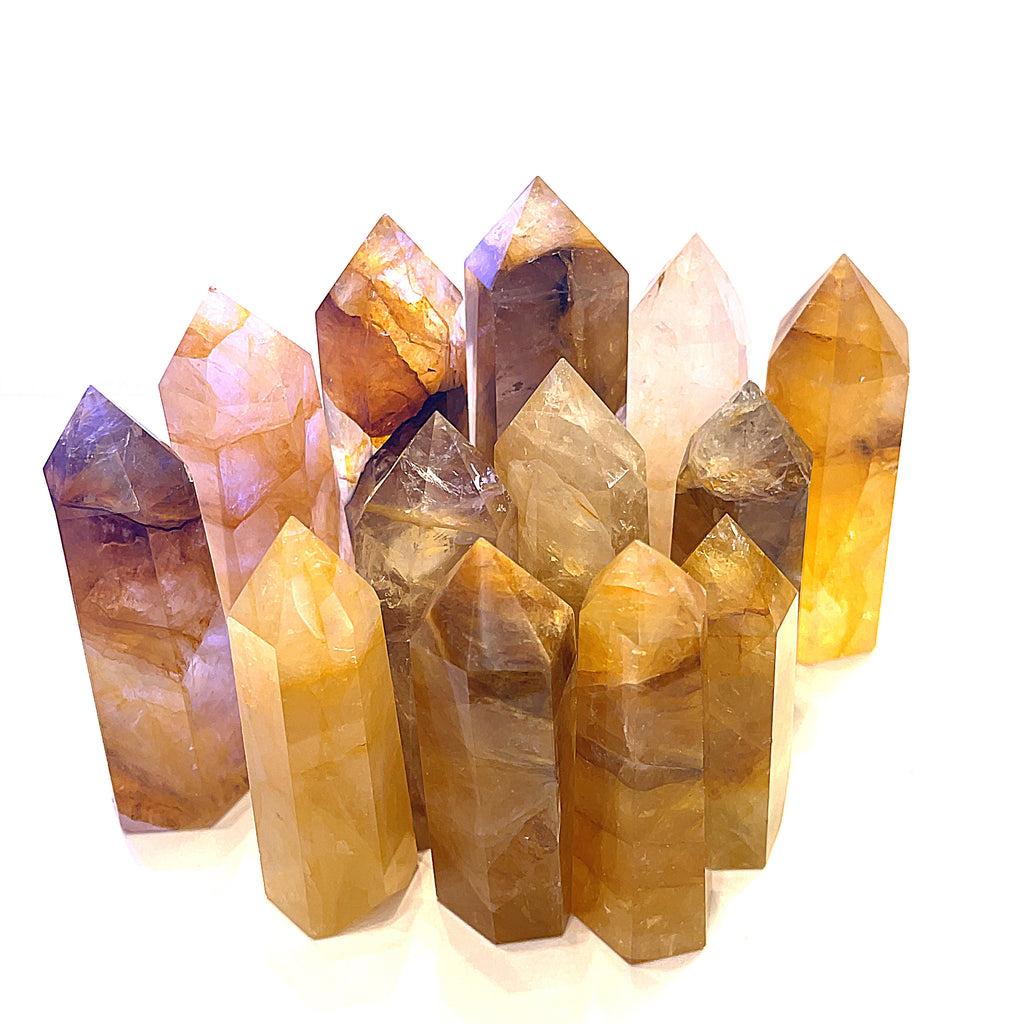 A collection of Golden Healer Quartz gemstone towers displayed together on a white background front overview. 
