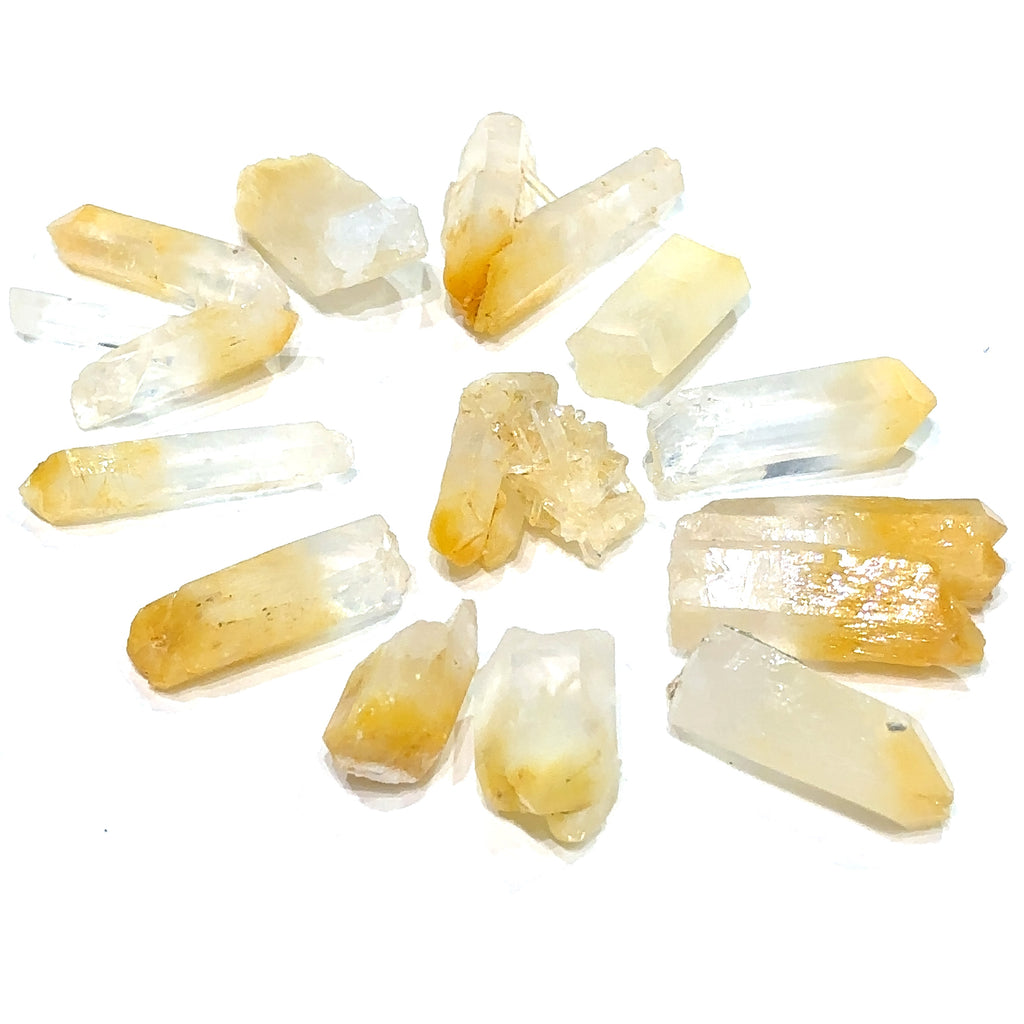 A collection of Halloysite-Included Quartz gemstones, also known as 'Mango Quartz', is displayed on a white surface center overview. 