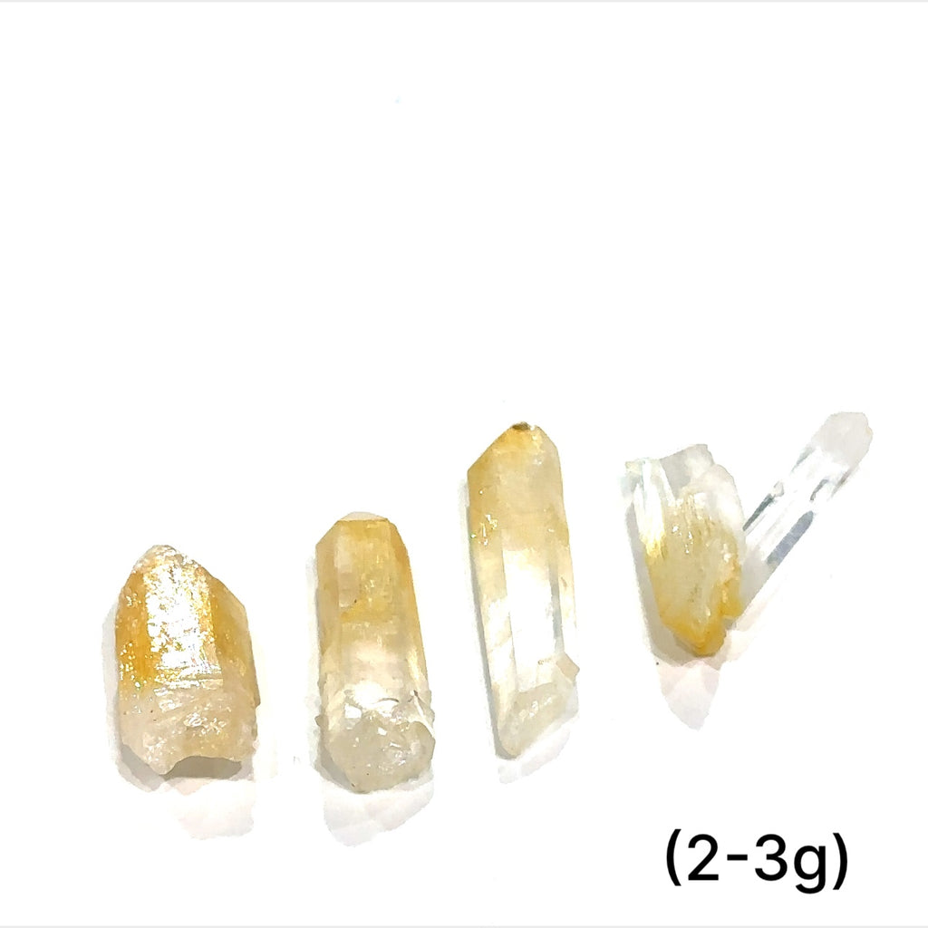 A collection of Halloysite-Included Quartz gemstones, also known as 'Mango Quartz', sizes (2-3g) is displayed on a white surface center overview.