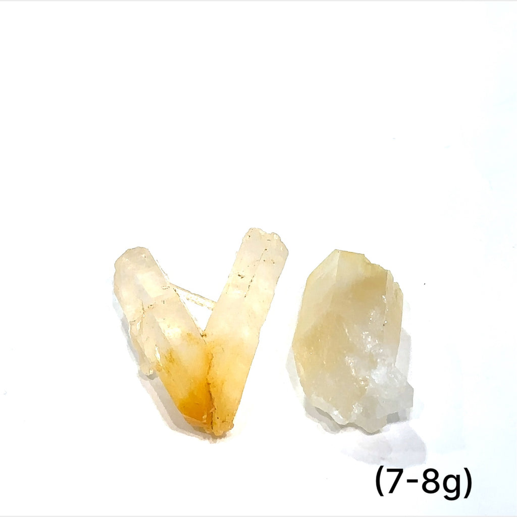 A collection of Halloysite-Included Quartz gemstones, also known as 'Mango Quartz', sizes (7-8g) is displayed on a white surface center overview.