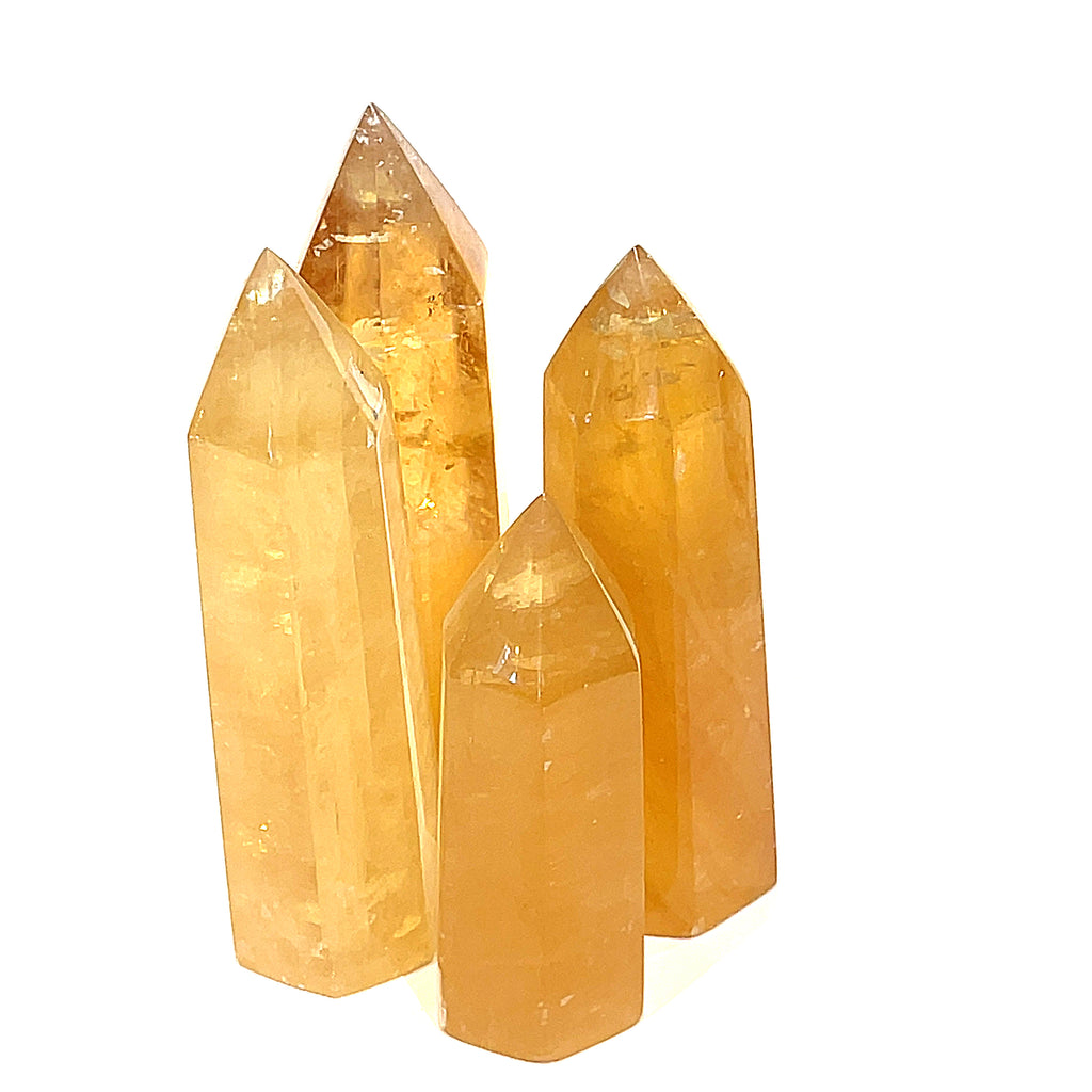 A collection of Honey Calcite gemstone towers displayed together on a white background, front view.