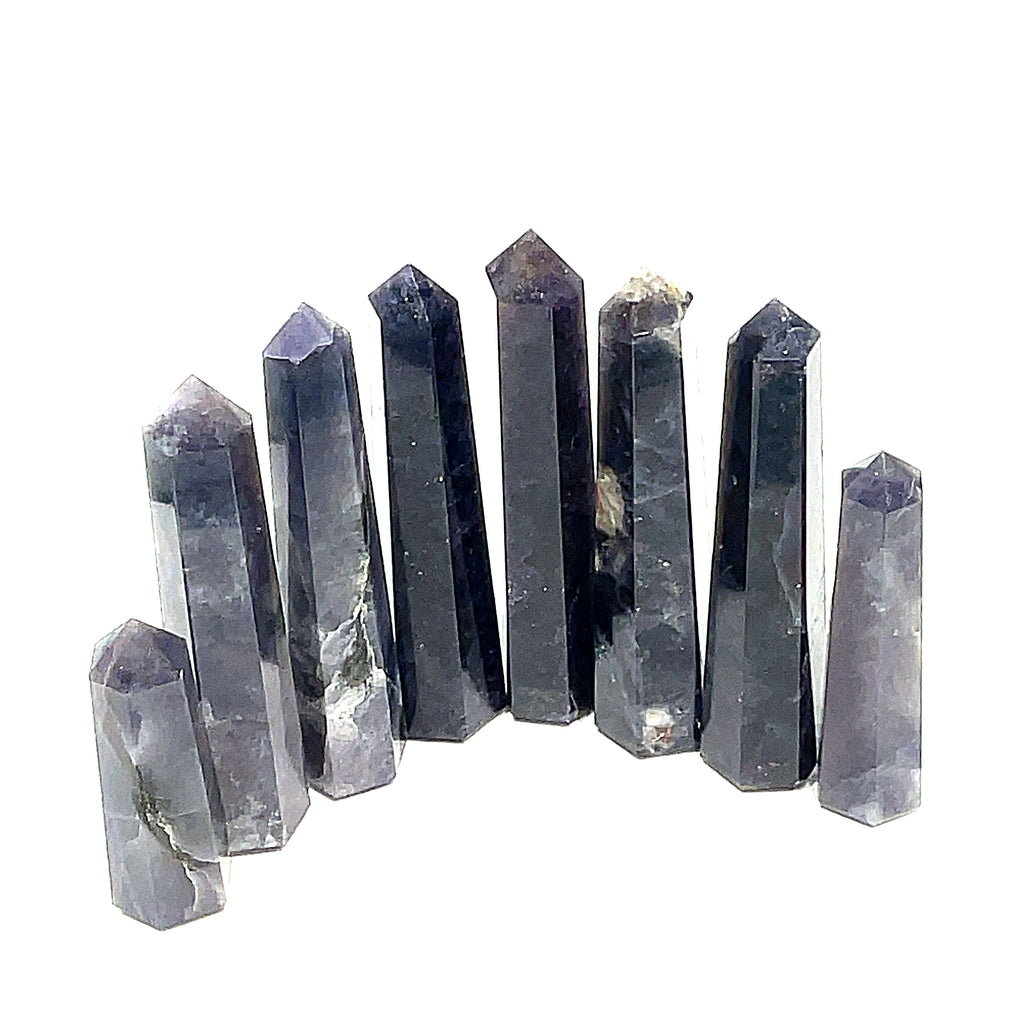 A collection of Iolite gemstone towers displayed in a row, showing variations in color from light to deep blue with a purplish tint on a white background, front view. 