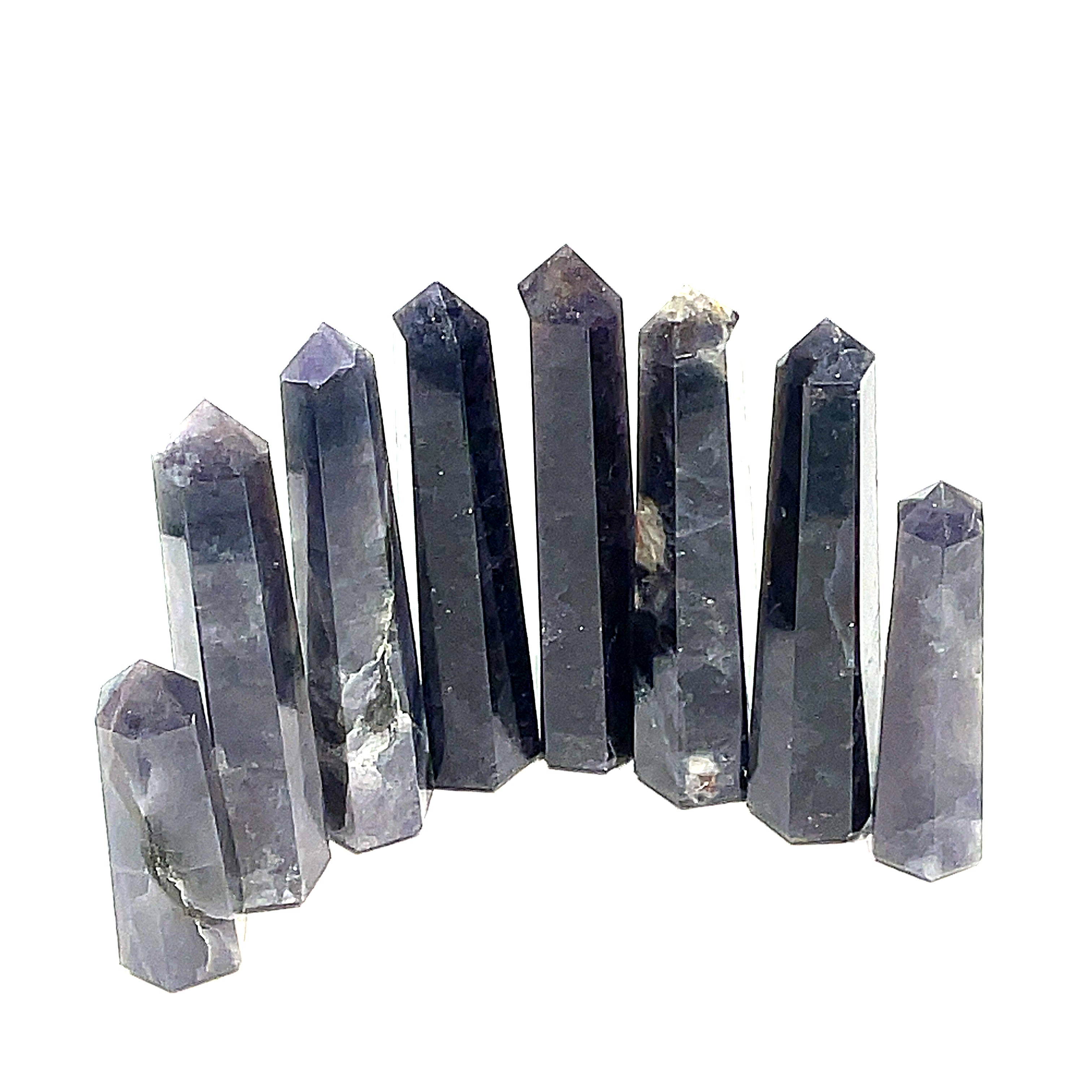A collection of Iolite gemstone towers displayed in a row, showing variations in color from light to deep blue with a purplish tint on a white background, front view. 