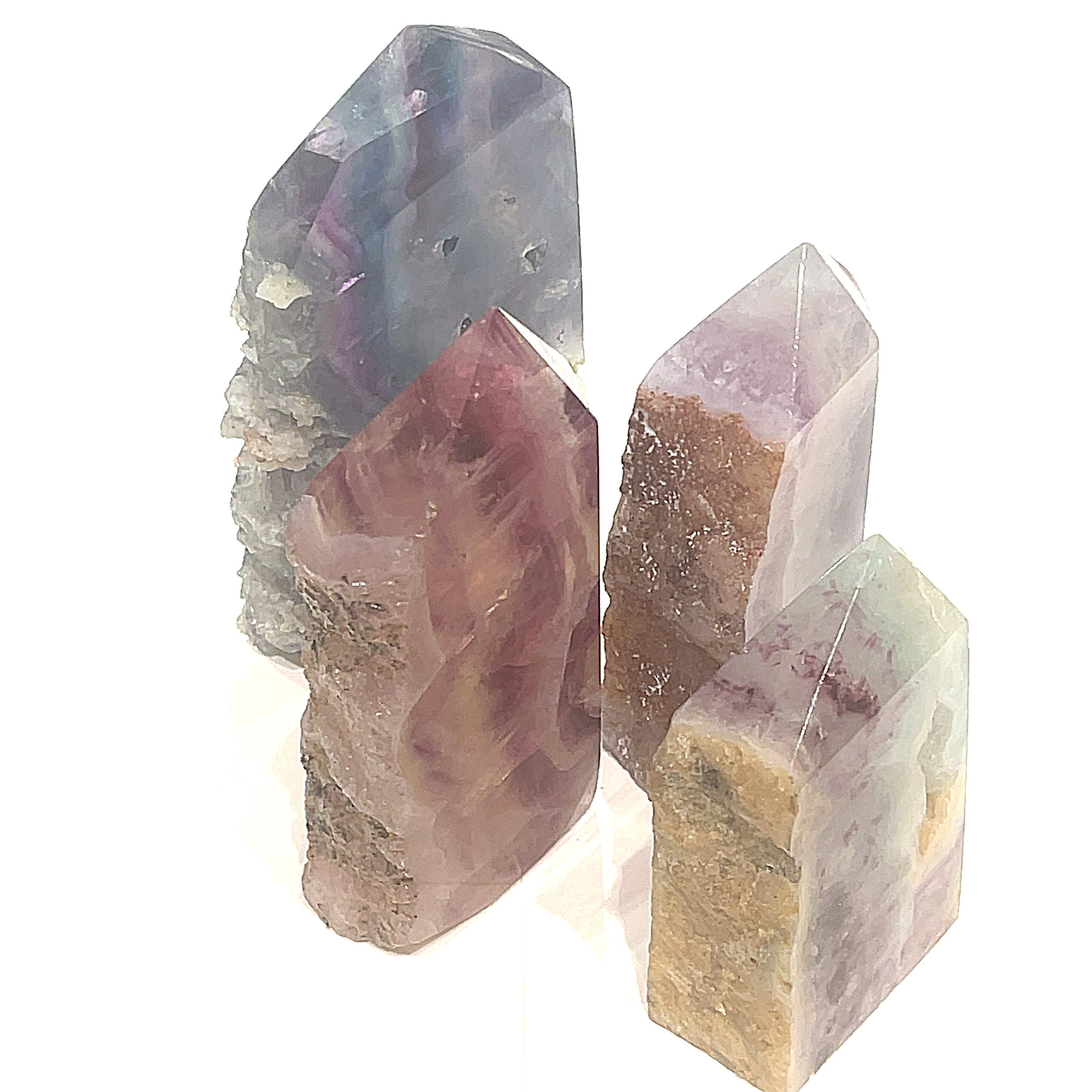 A collection of Rainbow Fluorite Slab gemstone towers in varying sizes, displaying a banding of colors, including purple and blue on a white background, front slight angle view. 