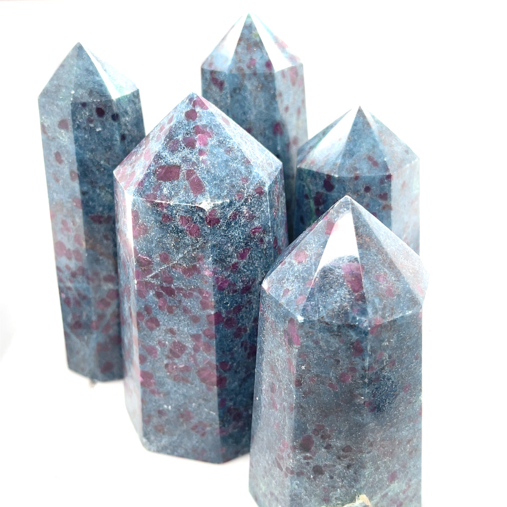 A collection of Ruby Kyanite gemstone towers with a deep blue color and red speckles, displayed on a white background, front overview.