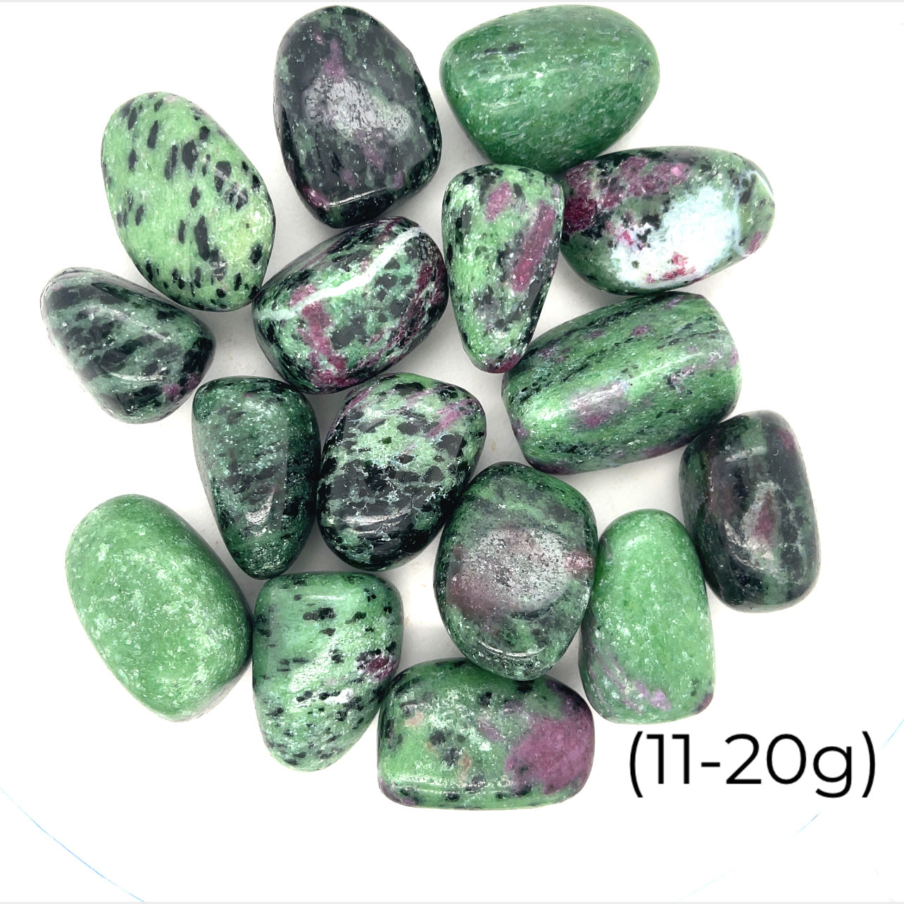 A collection of Ruby in Zoisite tumbled gemstones varying in shades of green with hints of purple, displayed on a white surface. The size of the stones is indicated as 11-20 grams.