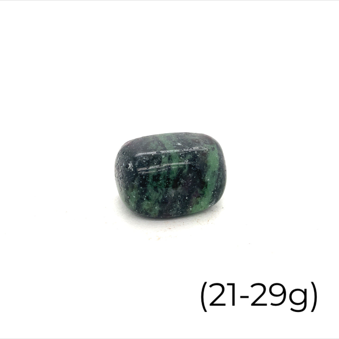 A collection of Ruby in Zoisite tumbled gemstones varying in shades of green with hints of purple, displayed on a white surface. The size of the stones is indicated as 21-29 grams.