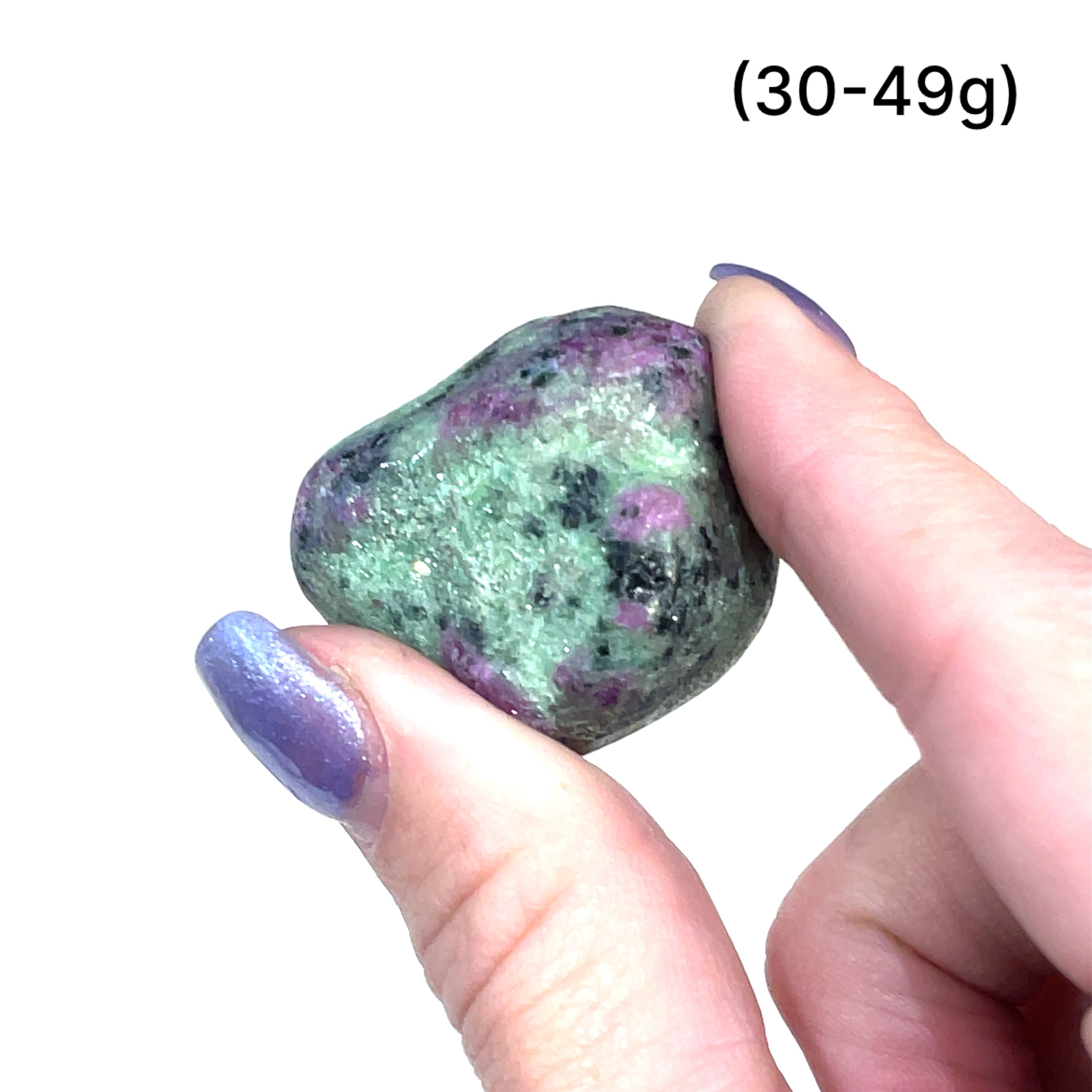 A collection of Ruby in Zoisite tumbled gemstones varying in shades of green with hints of purple, displayed on a white surface. The size of the stones is indicated as 30-49 grams.