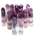 A collection of Watermelon Fluorite Gemstone Towers arranged together, displaying a mix of purple and green colors on a white background, front view. 