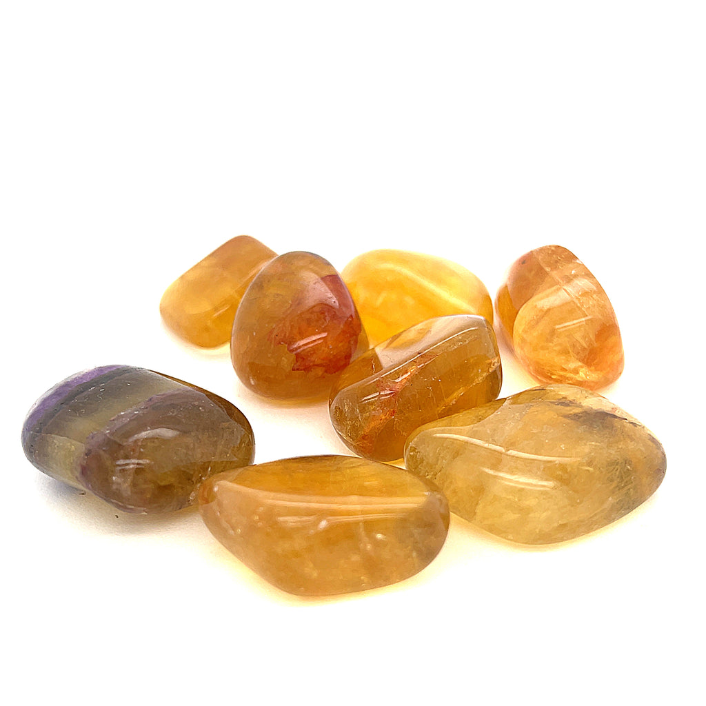 A collection of Yellow Fluorite tumbled gemstones displayed on a white surface, front overview. 
