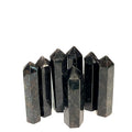 A collection of black Arfvedsonite gemstone towers arranged together on a white background, front, close up view. 