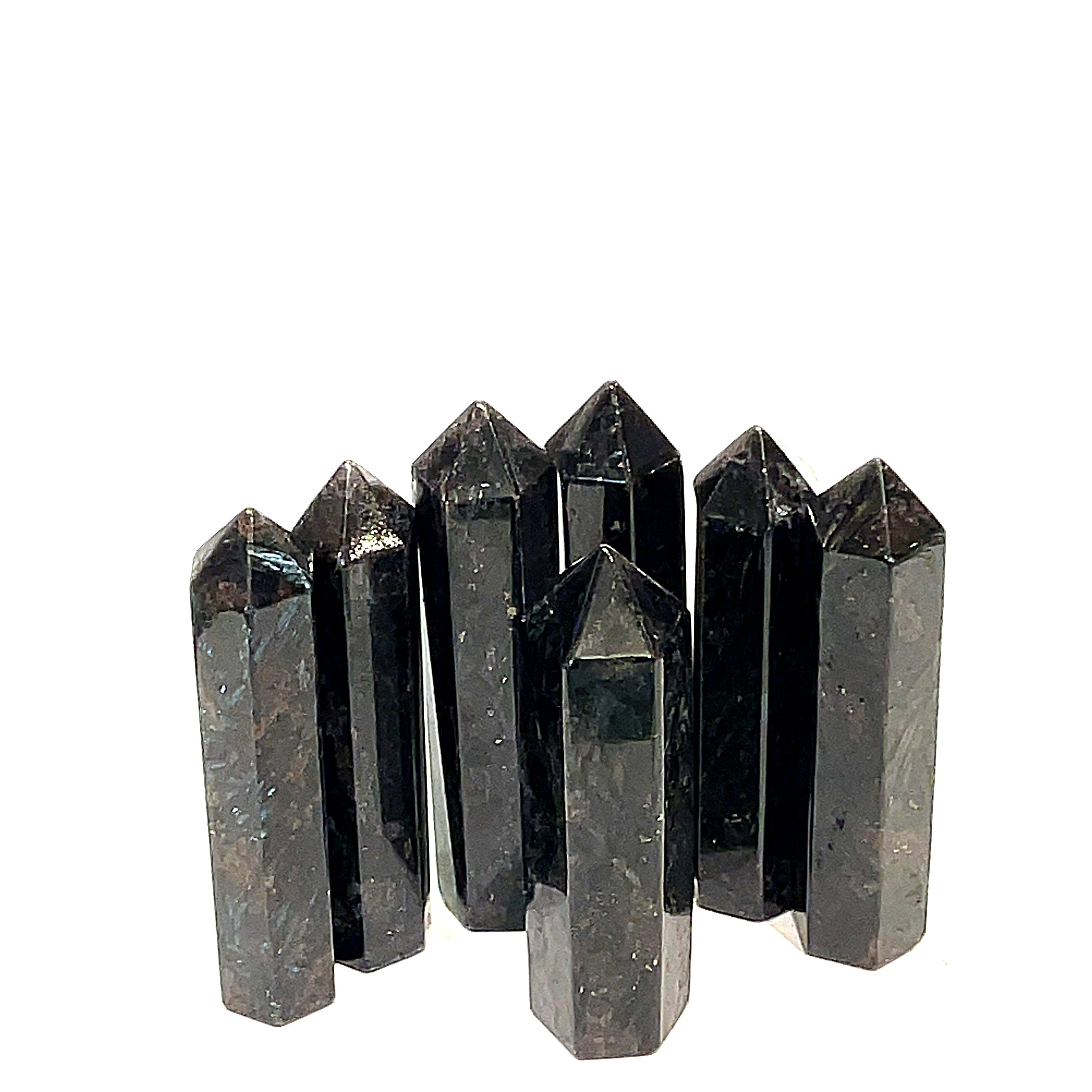 A collection of black Arfvedsonite gemstone towers arranged together on a white background, front, close up view. 